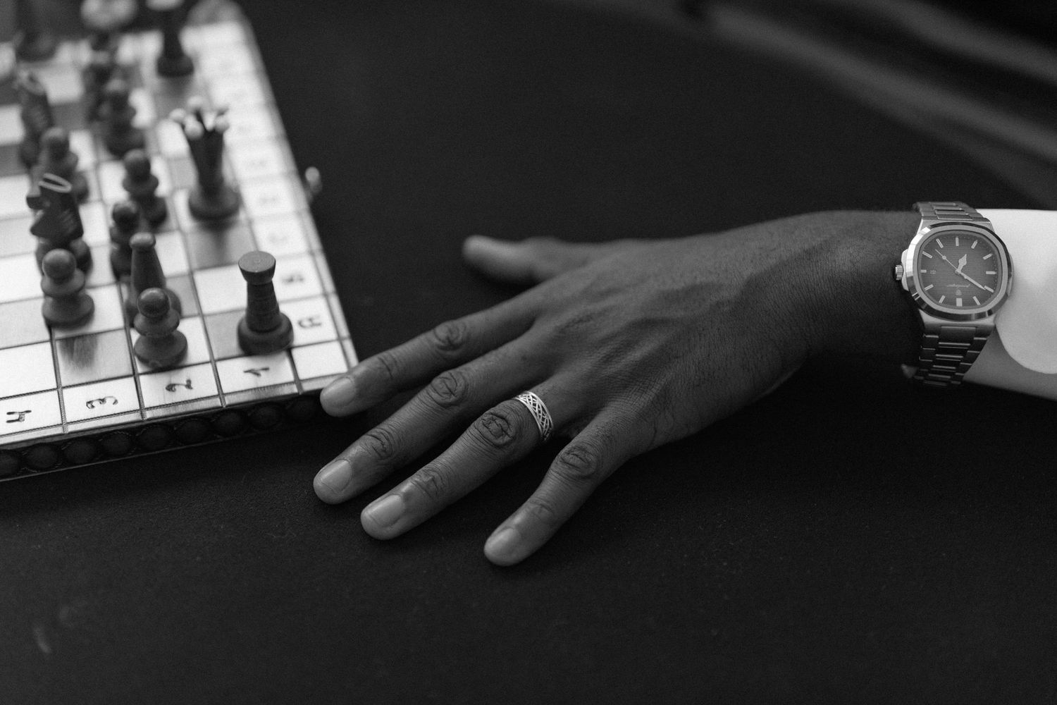 Close-up of hands playing piano keys in dramatic black and white lighting.