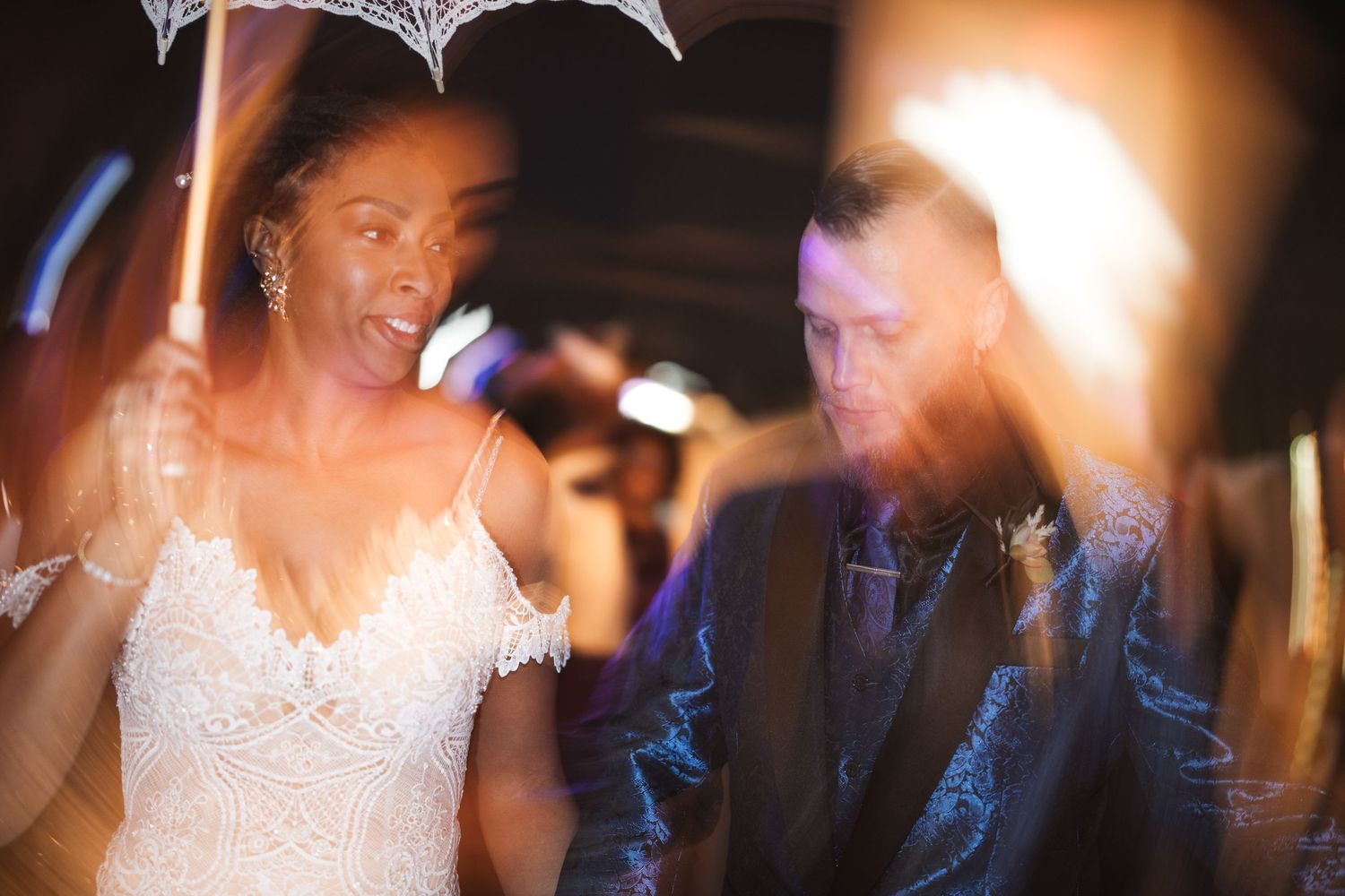 A bride and groom share their first dance together at a wedding reception with soft lighting and guests in the background.