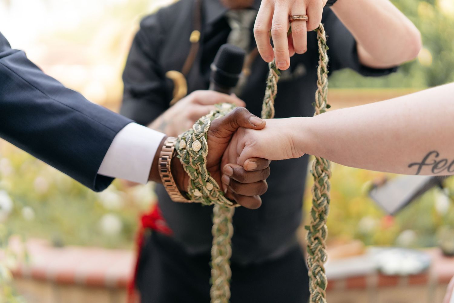 Wedding couple performing traditional handfasting ceremony with braided cord.