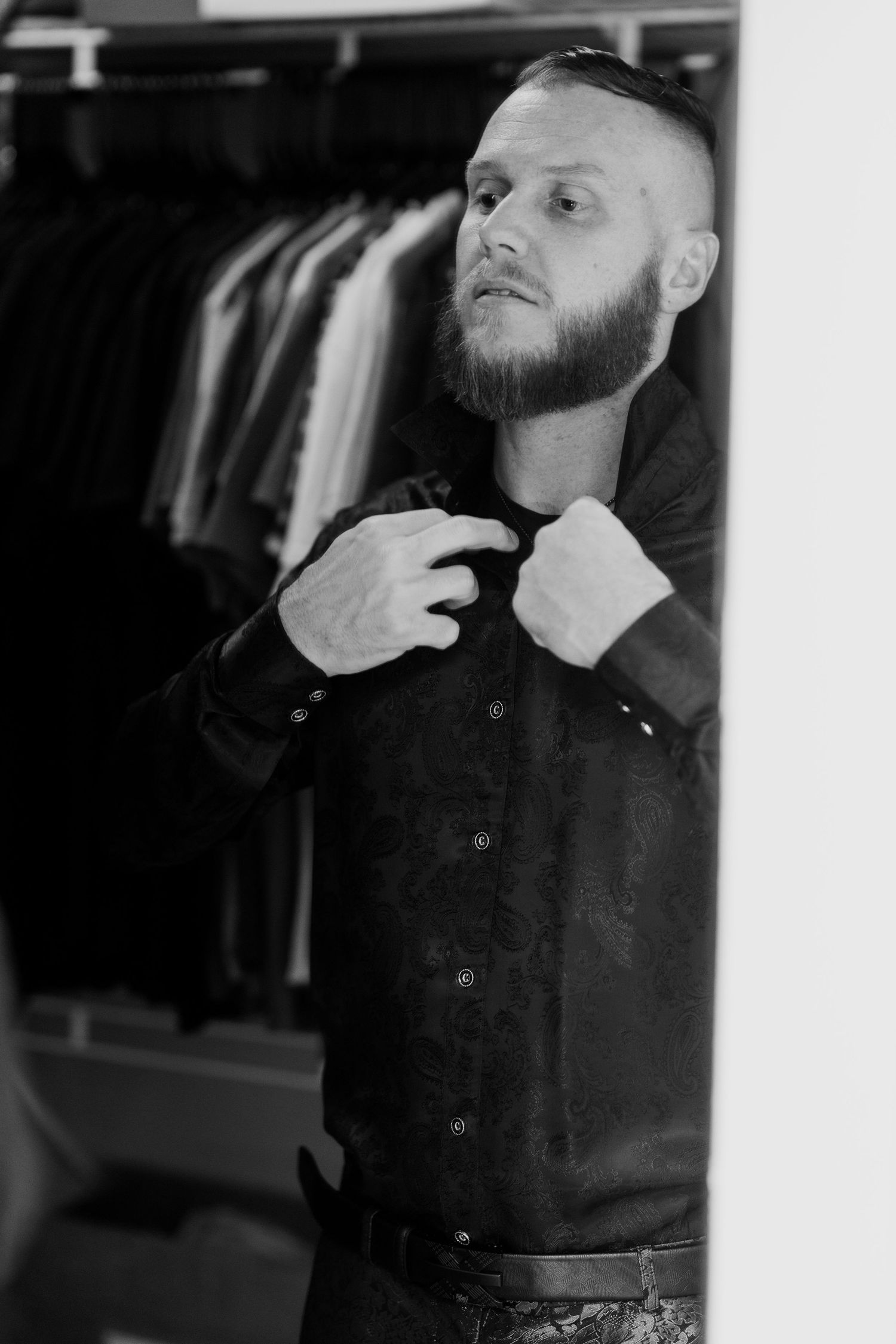 A black and white portrait showing someone in dark clothing against a light background.