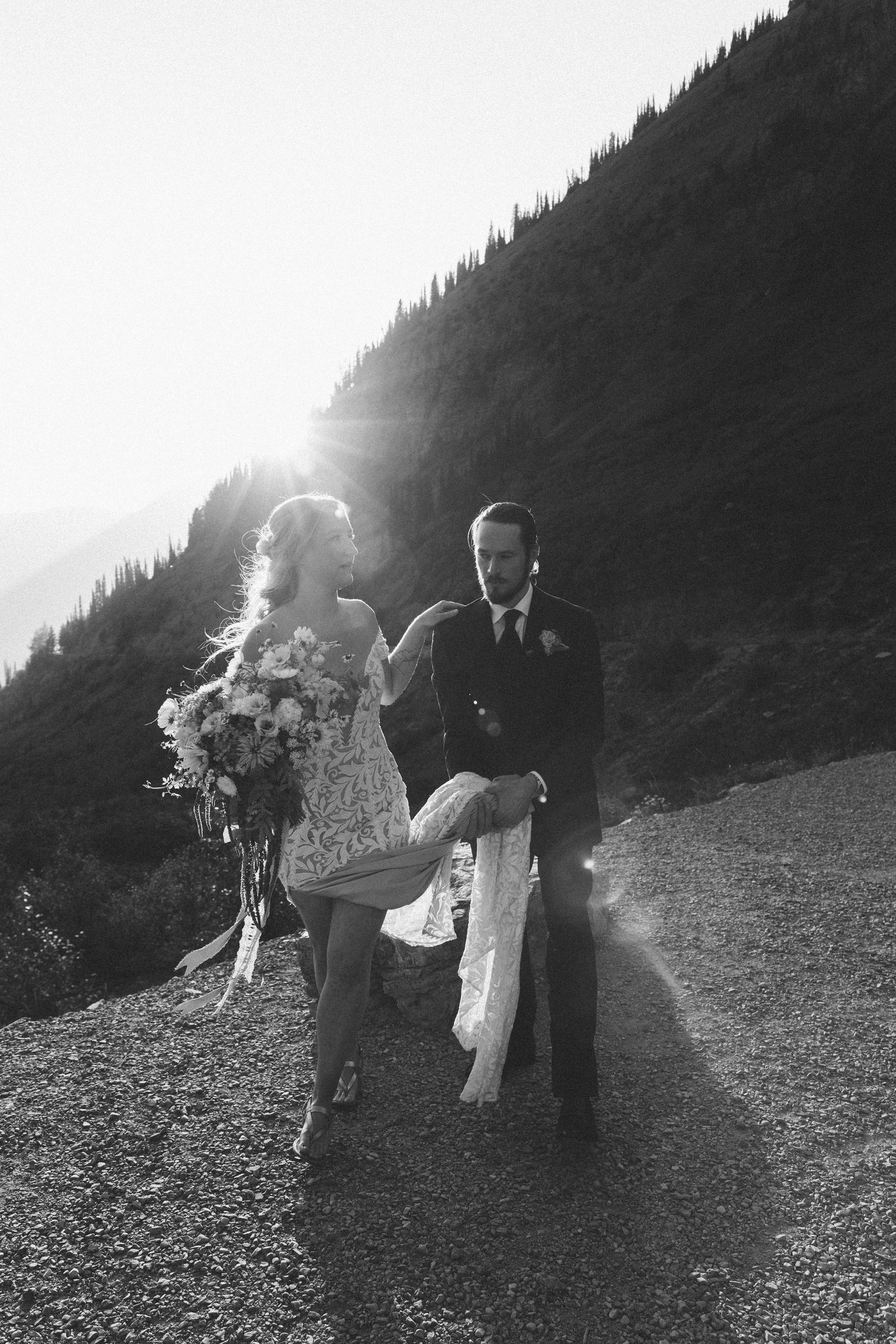 A couple walks along a misty mountain slope in black and white, creating a dreamy romantic silhouette effect.