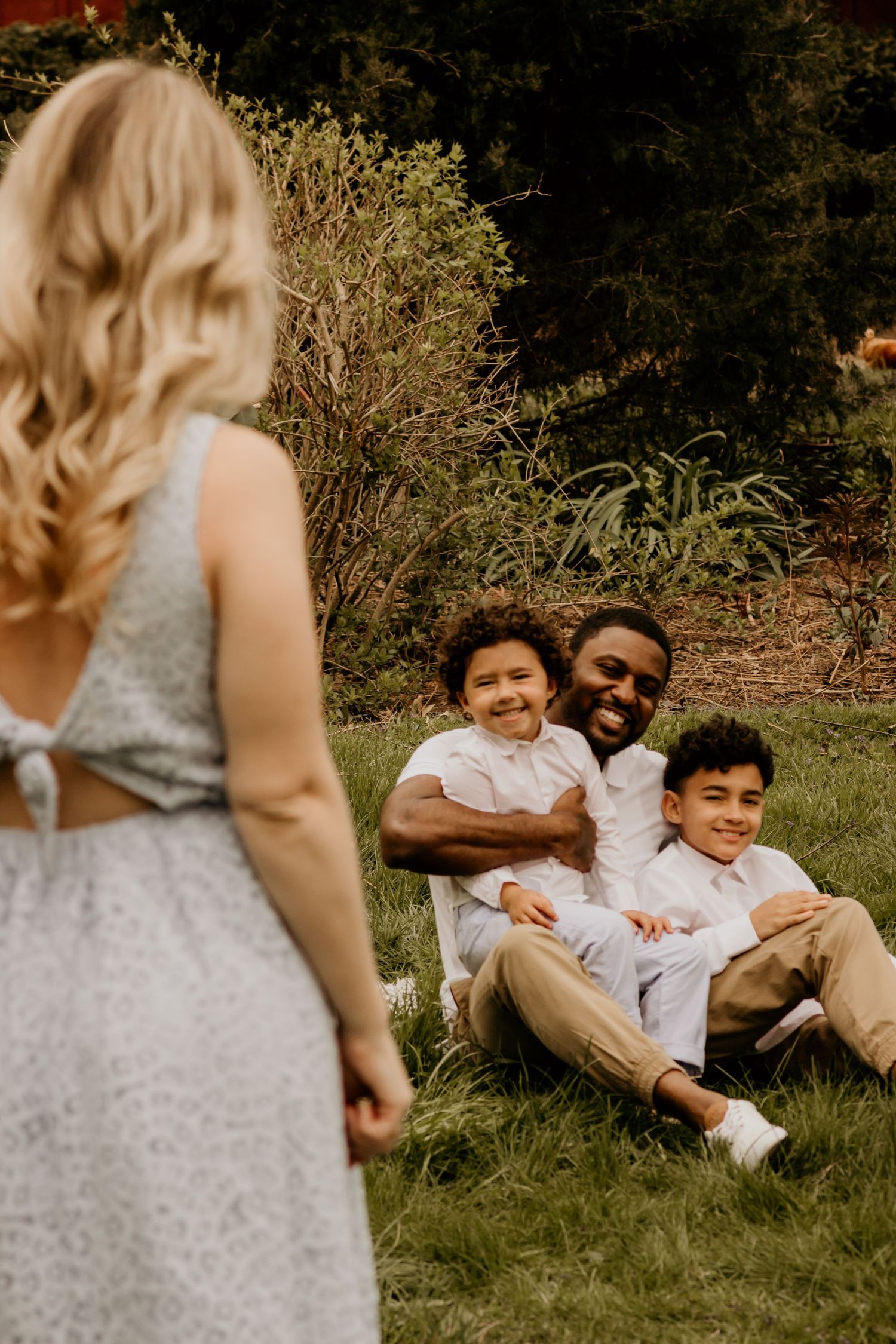 Family enjoying quality time together while relaxing on green grass in a garden setting.