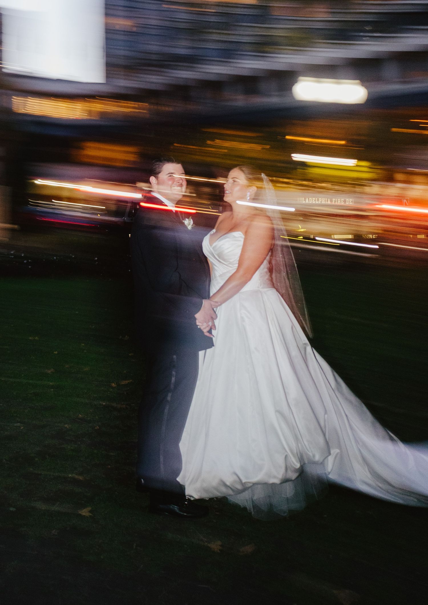 Motion blur captures a romantic wedding couple dancing at night with streaks of light creating a dreamy effect.