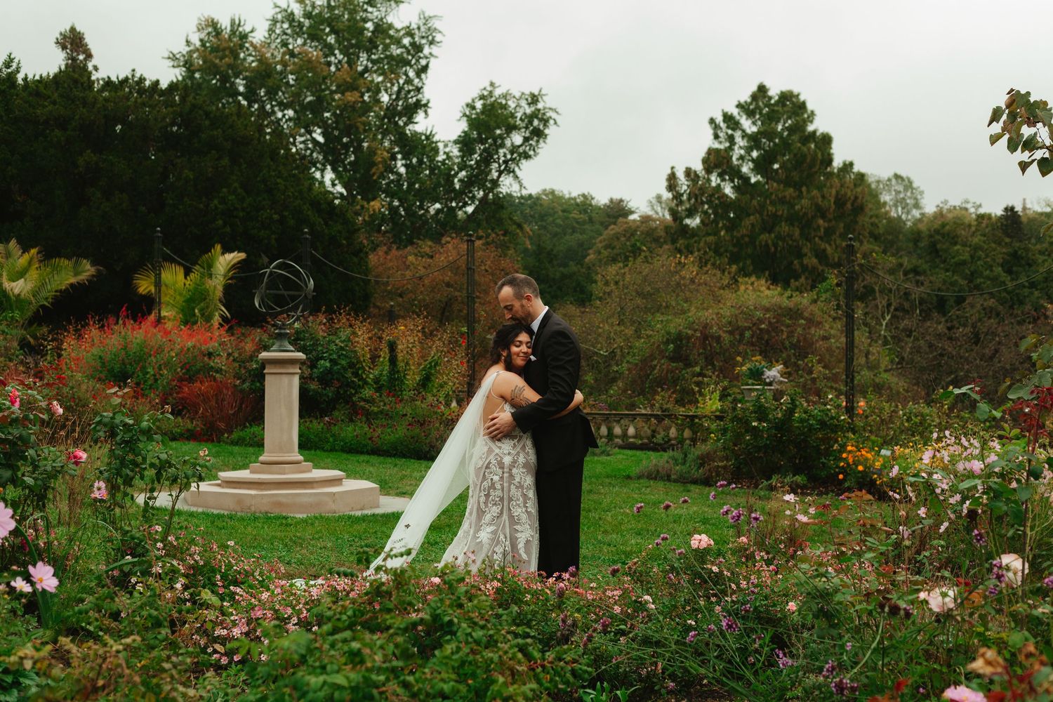 A romantic garden wedding scene with couples embracing among blooming flowers and lush greenery in an outdoor setting.