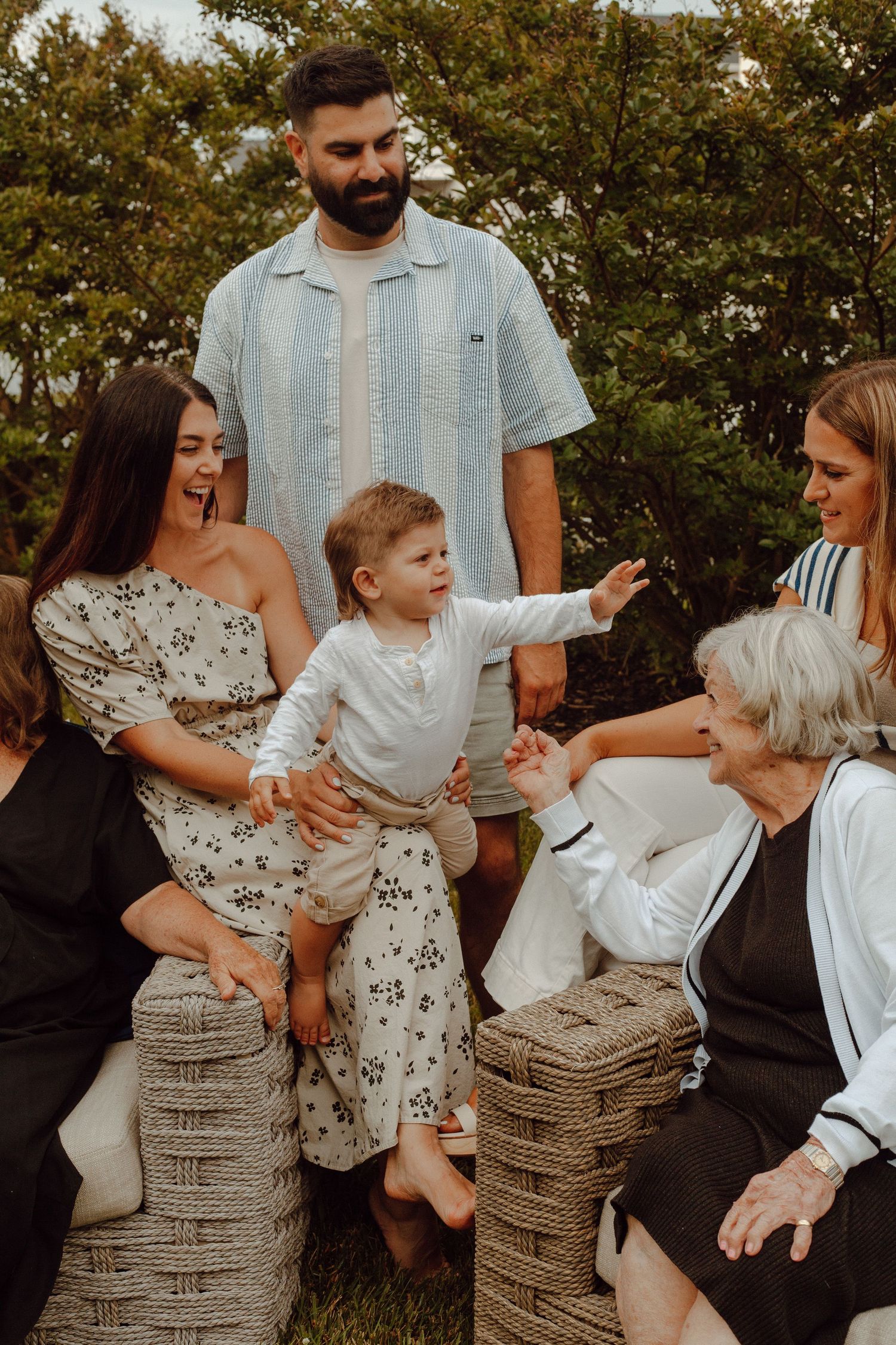 A family gathering outdoors with a small child reaching out while surrounded by wicker baskets.