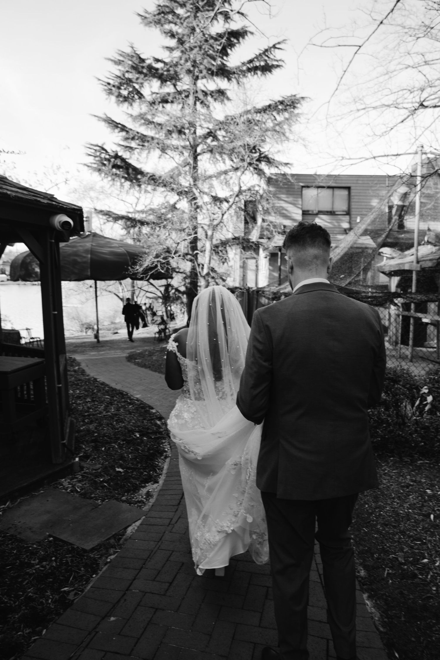 A wedding couple walking along a brick path on a winter day in black and white.