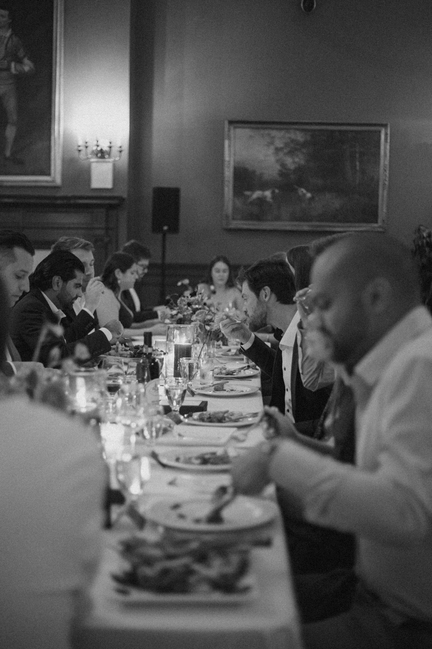 Guests gather around an elegant dinner table at a formal event in black and white.