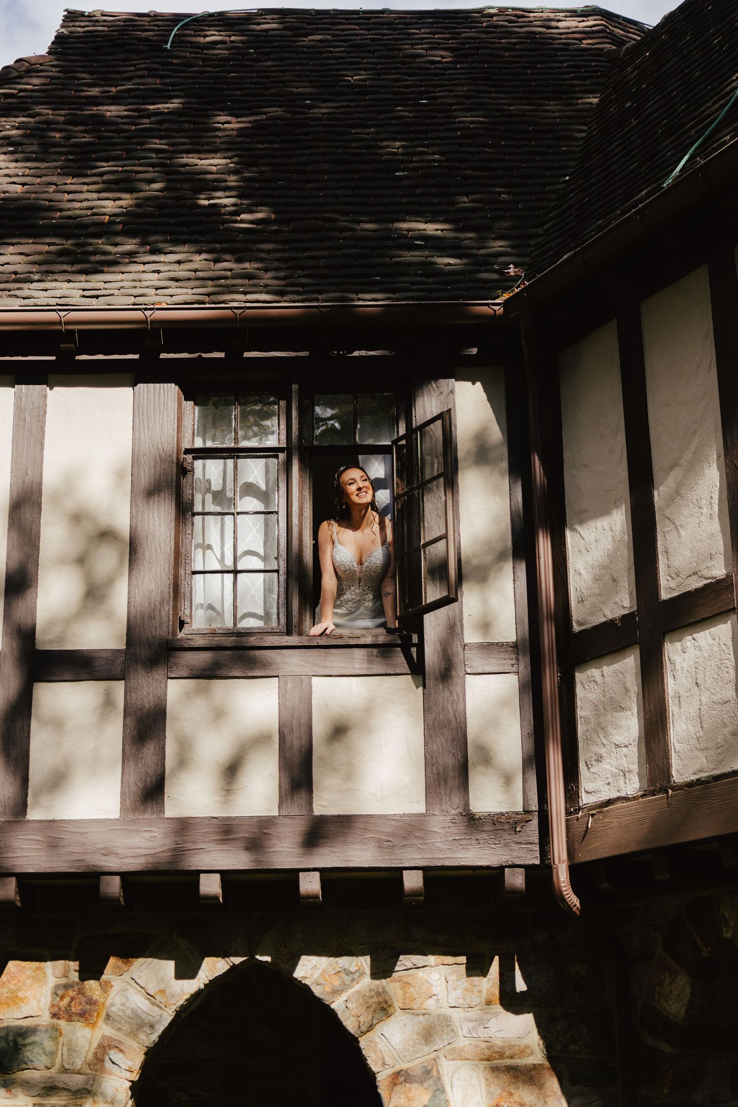 A rustic Tudor-style house exterior with white walls, dark timber framing, and stone foundation in dramatic lighting.