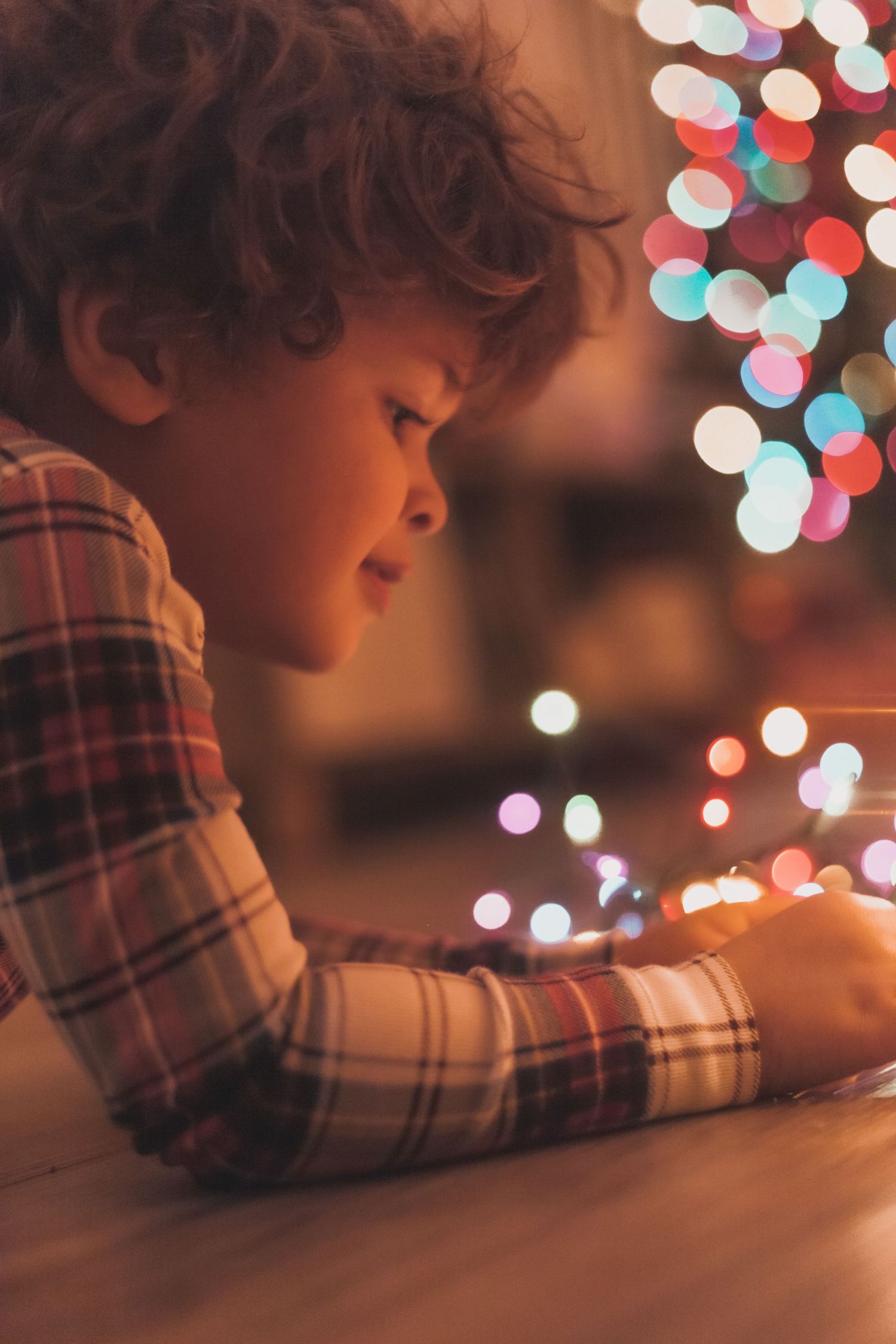 A child gazing at colorful holiday lights creating a magical bokeh effect.