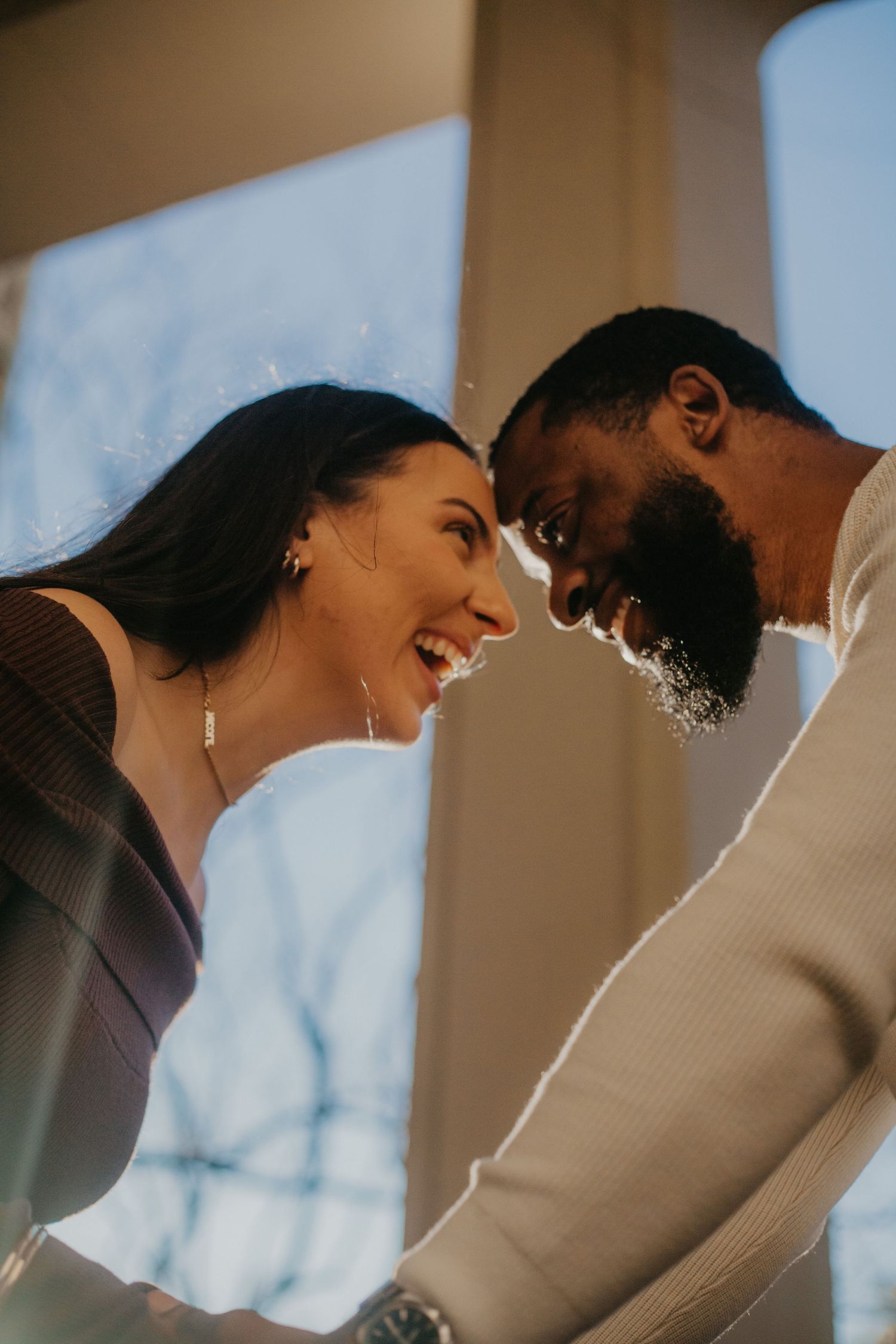 A romantic couple shares a joyful intimate moment while smiling at each other.