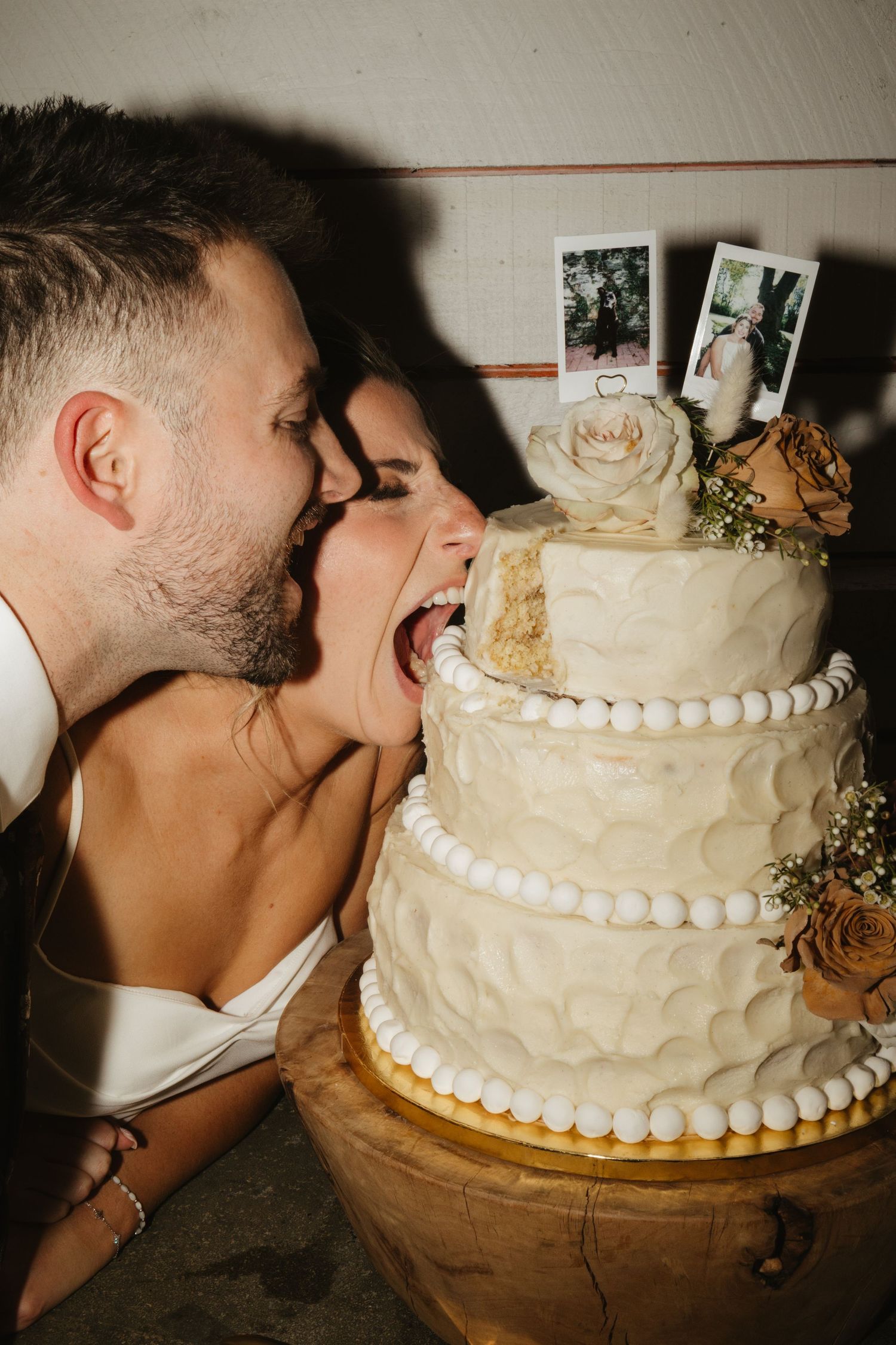 A sequence of photos showing a couple taking a playful bite of their white tiered wedding cake with pearl decorations.