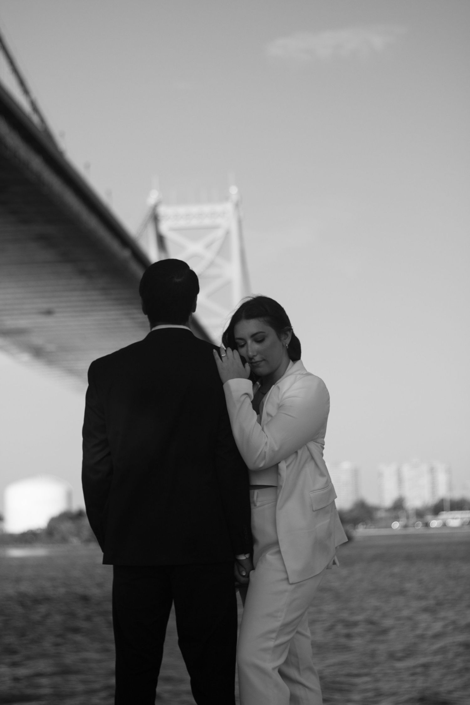 Romantic black and white photo of a couple by a bridge on their wedding day.