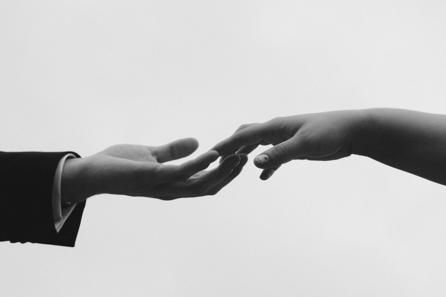 A sequence of black and white photographs showing hands reaching towards each other against a white background.