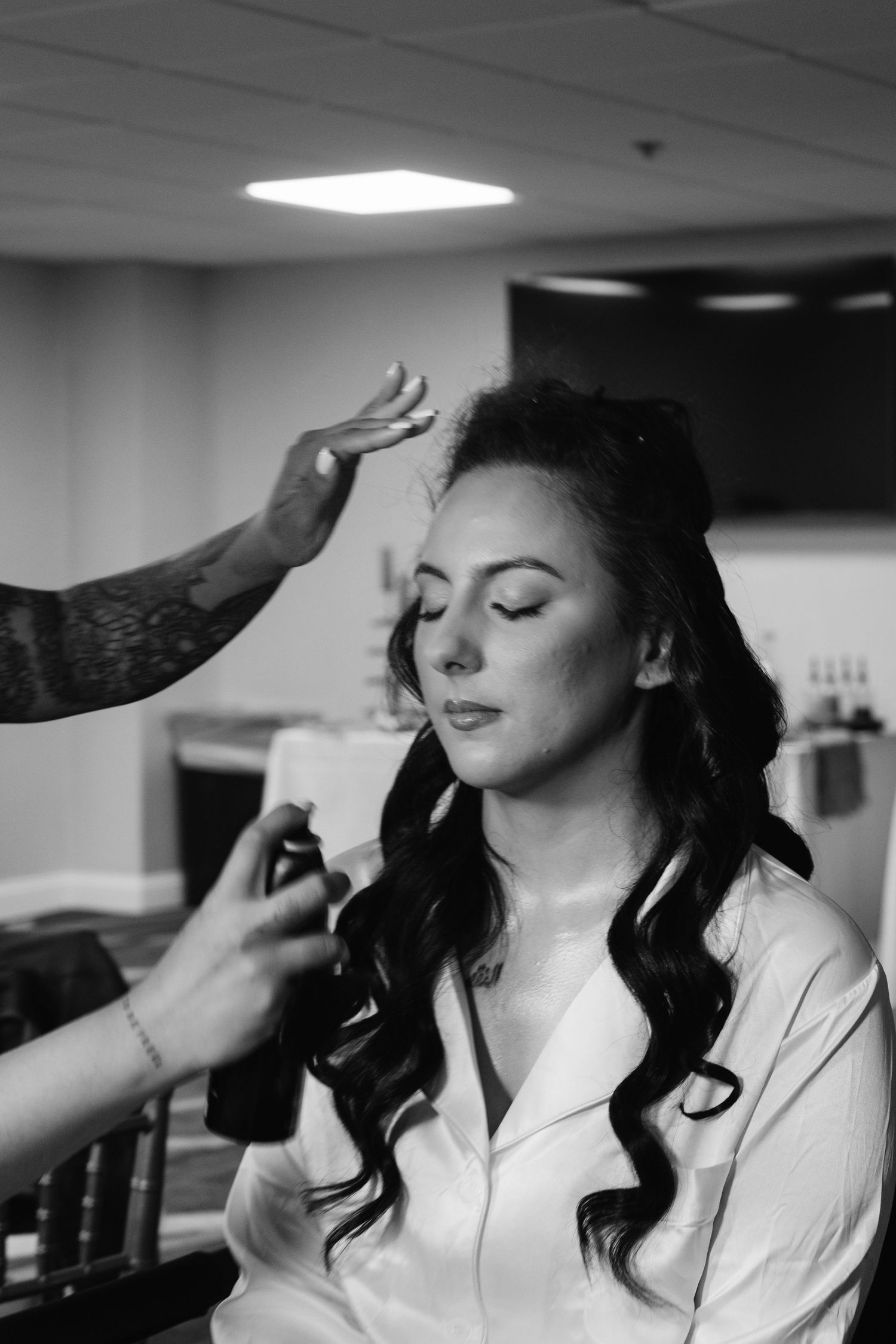 A professional makeup artist applies cosmetics during a black and white photoshoot.