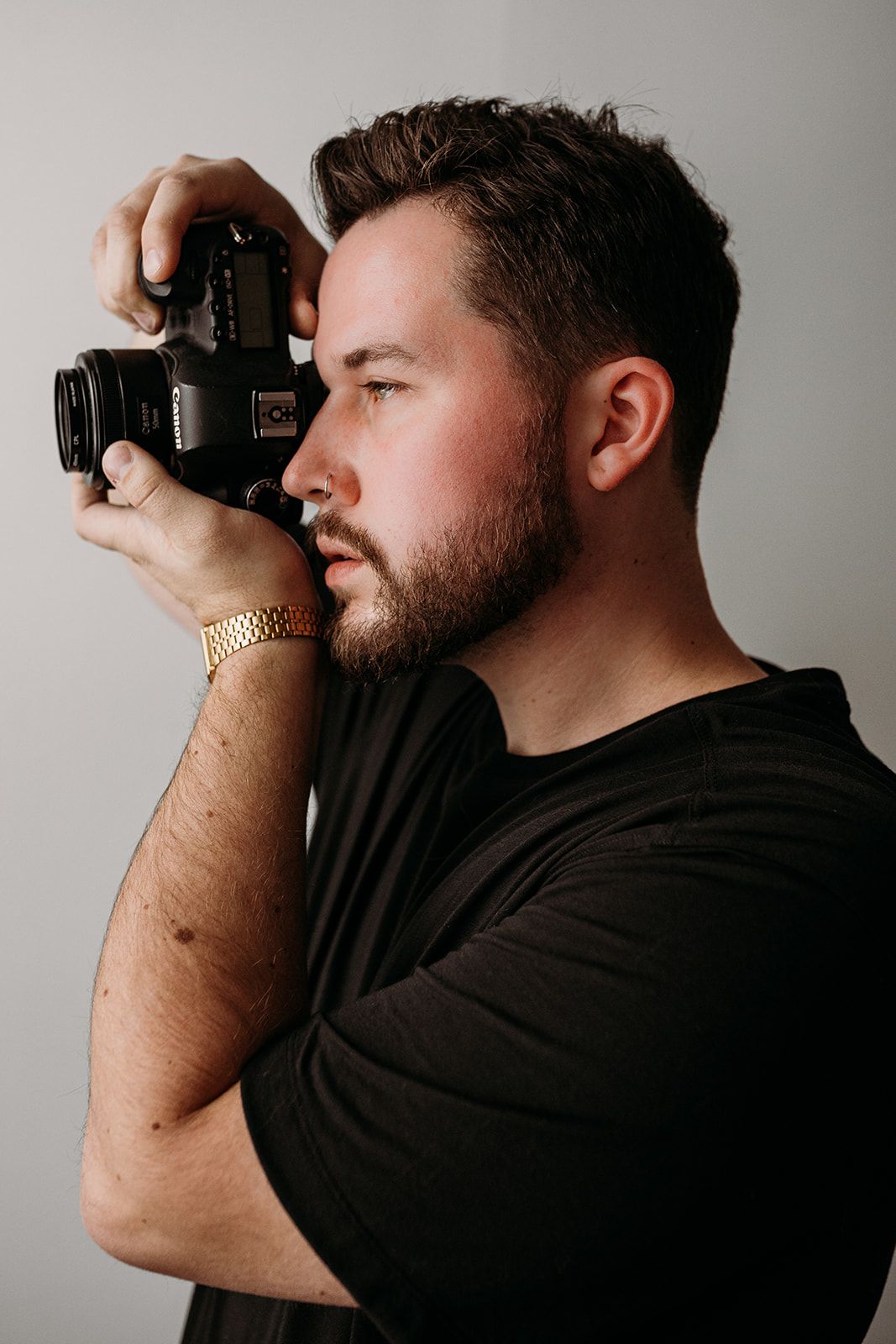 Side profile of photographer in black t-shirt taking picture with professional camera.