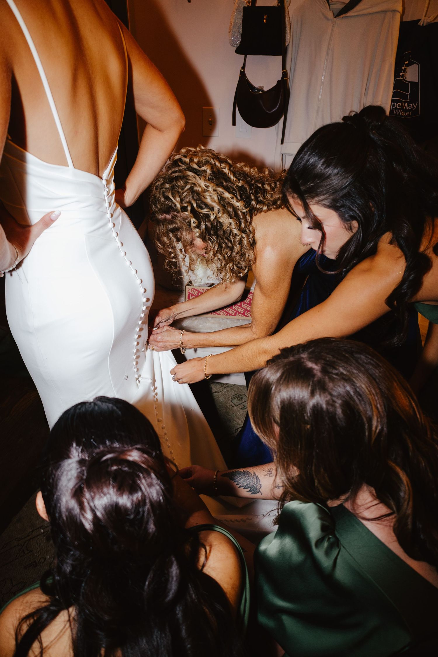 Behind the scenes fashion show preparation shows people helping with final dress adjustments backstage.