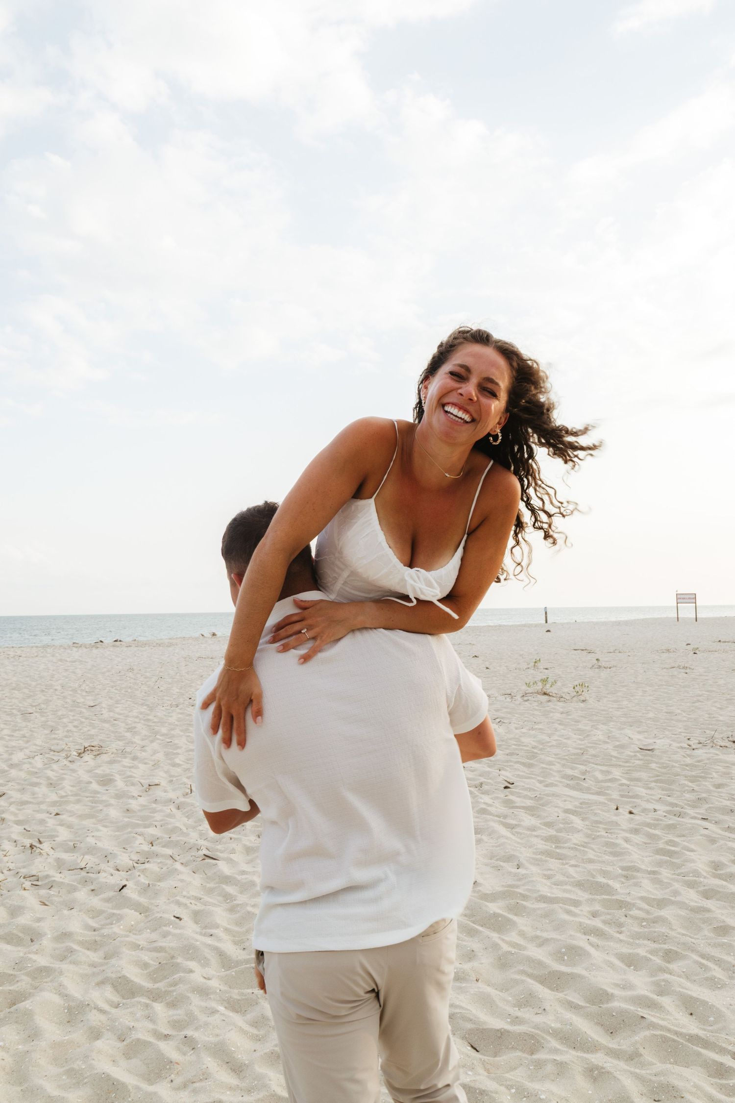 Series of playful shots showing dancing and movement on a white sandy beach in natural sunlight.