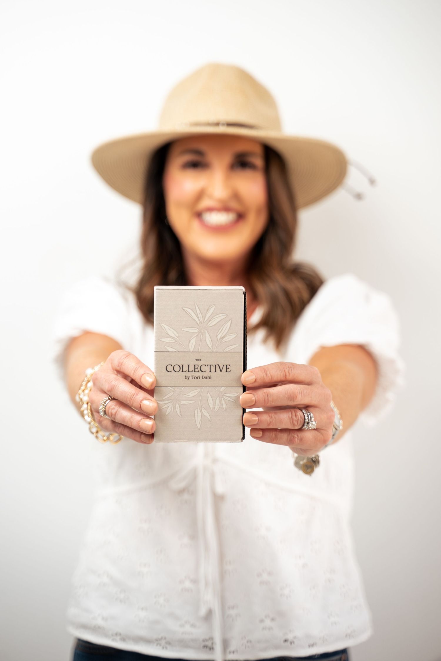 A series of photos showing hands holding a beige product box against a white background while wearing a white top and hat.