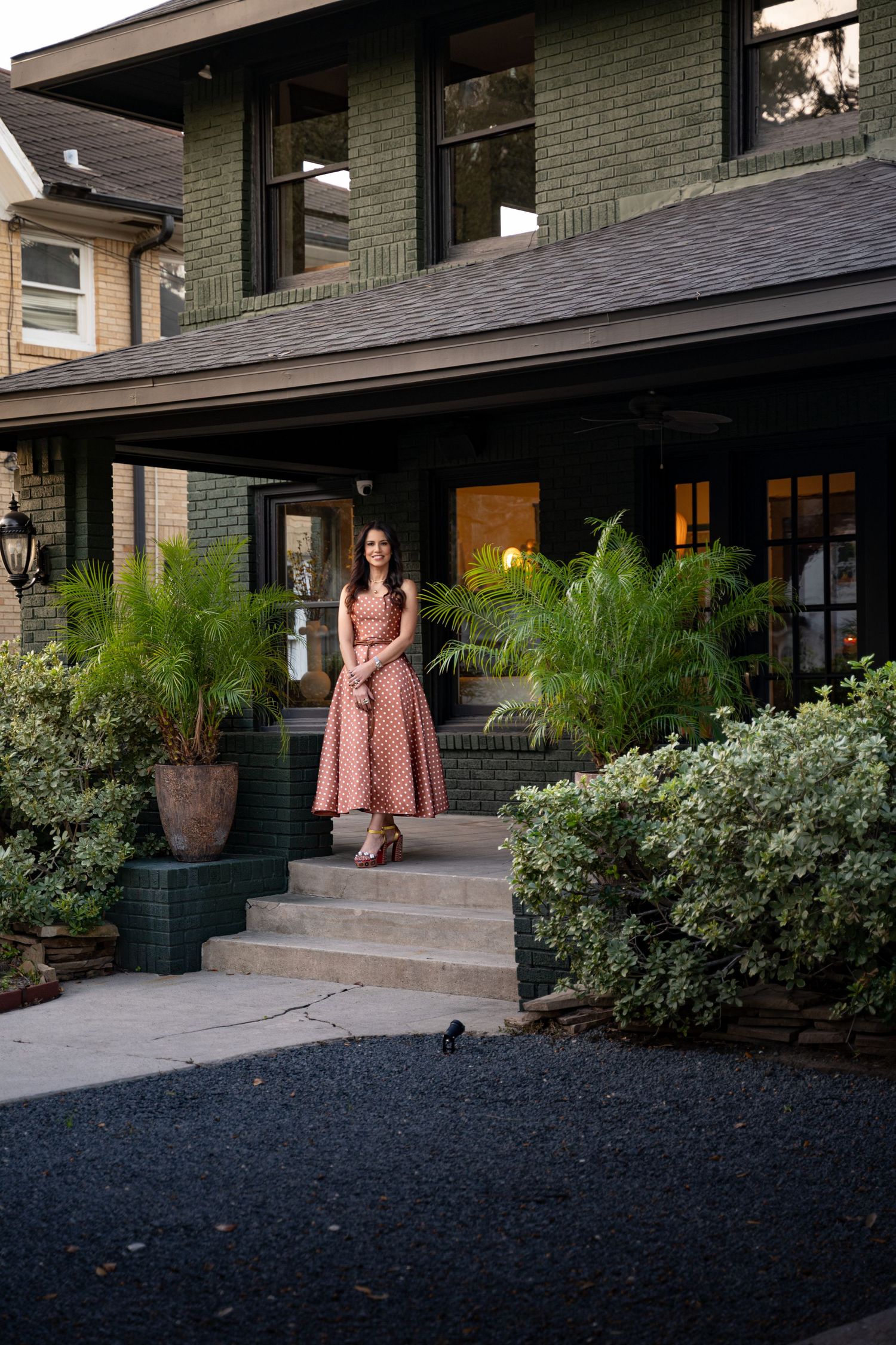 A sequence of four photos showing someone sitting on concrete steps outside a dark green brick house with landscaping.