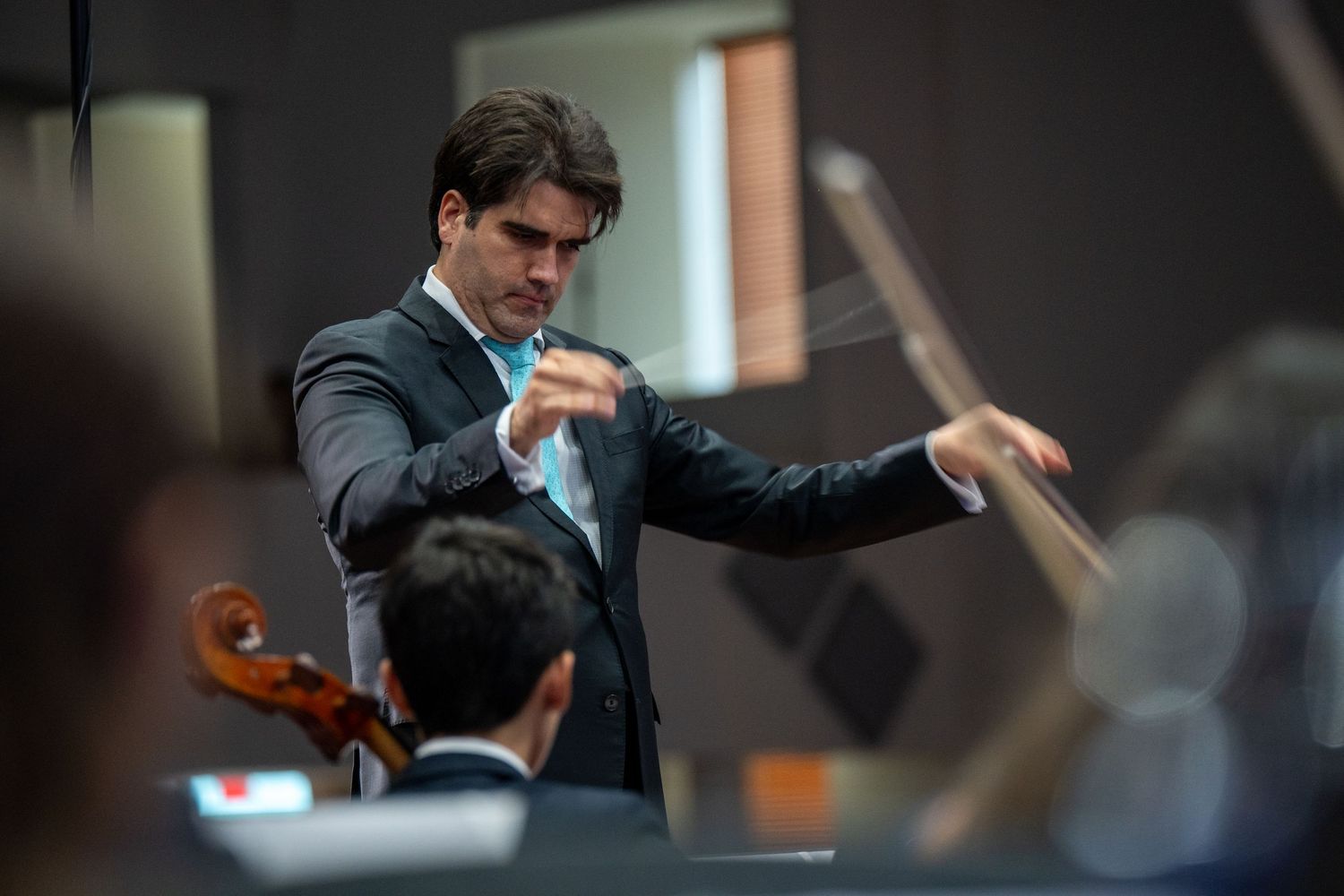 Professional musician playing violin with passionate expression during performance on dark stage.