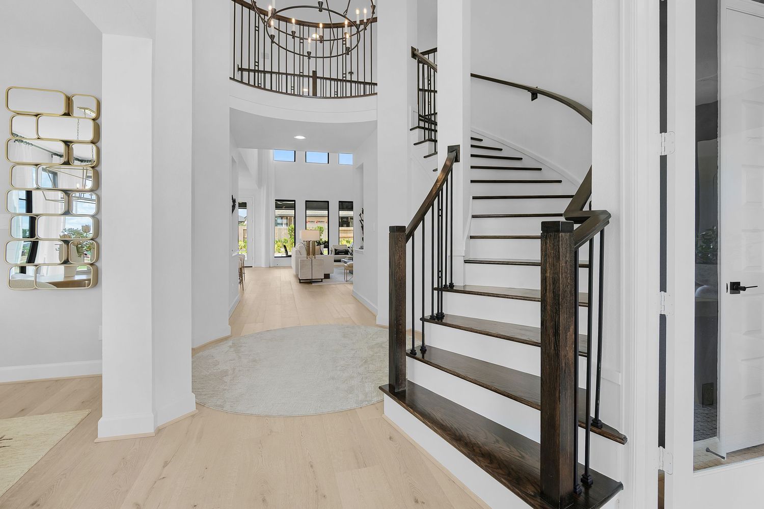 Modern white staircase with dark wood handrails and treads curves elegantly through a bright interior space.