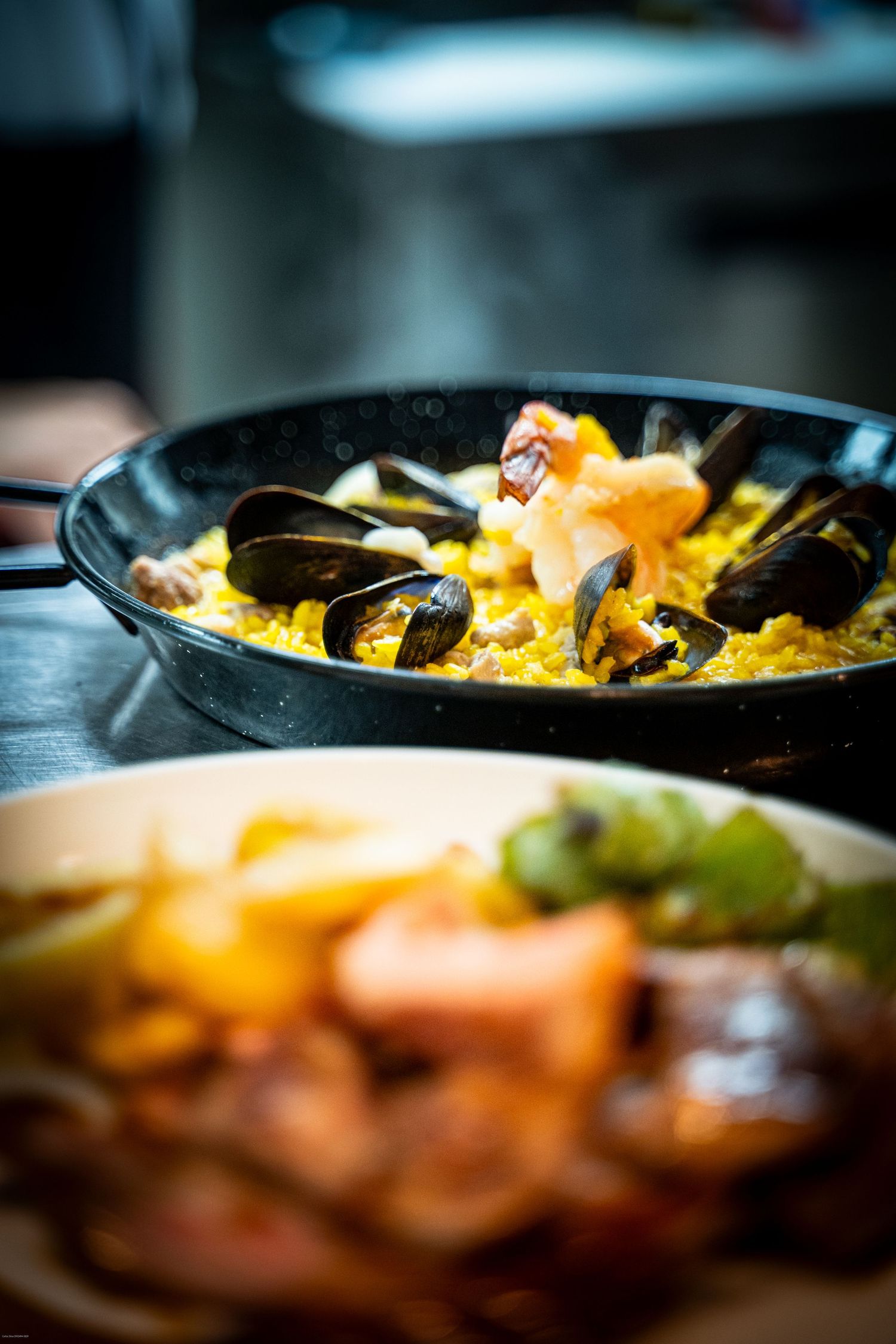 Close-up of seafood paella with mussels and saffron rice in a black pan.