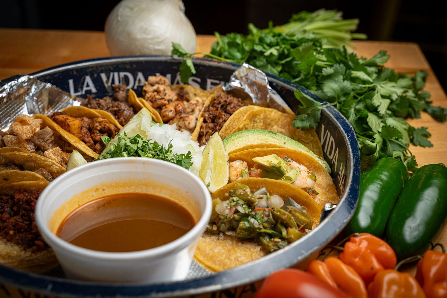 A bowl of steaming curry broth with fresh herbs and vegetables on the side awaits serving.