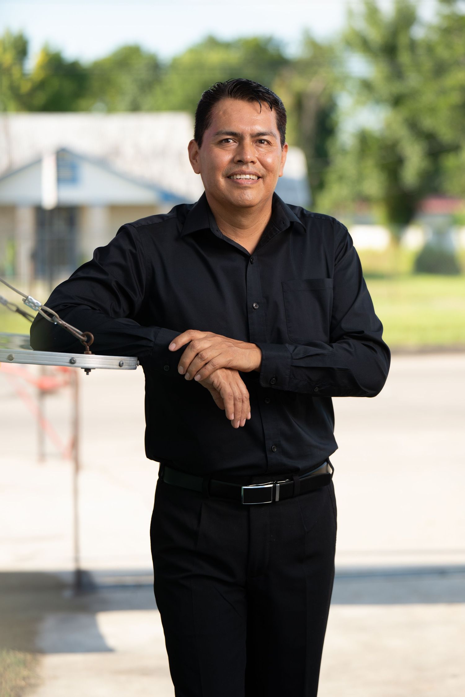 A person wearing all black clothing poses against an outdoor background across multiple portrait angles.
