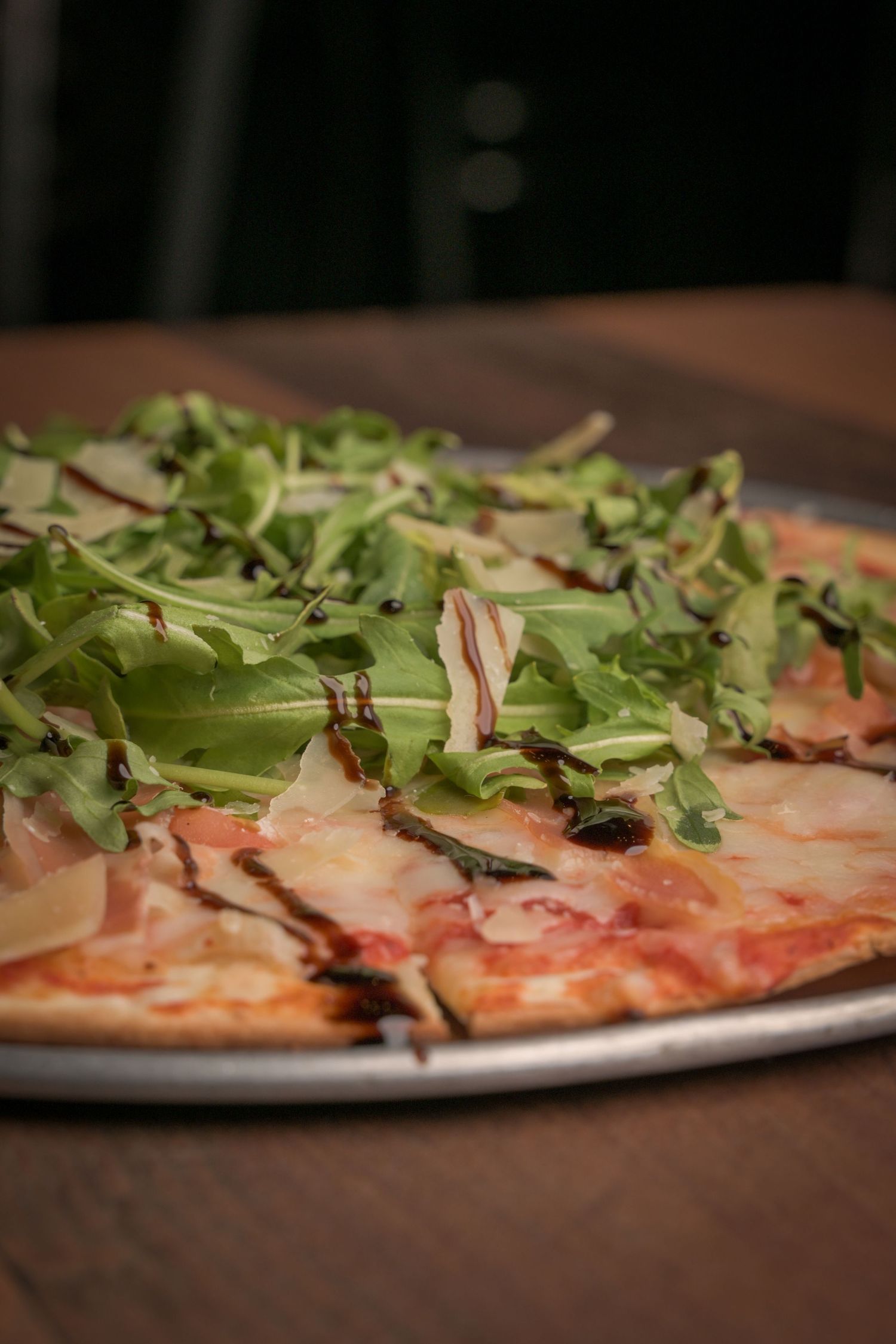 Thin crust pizza topped with arugula and prosciutto.