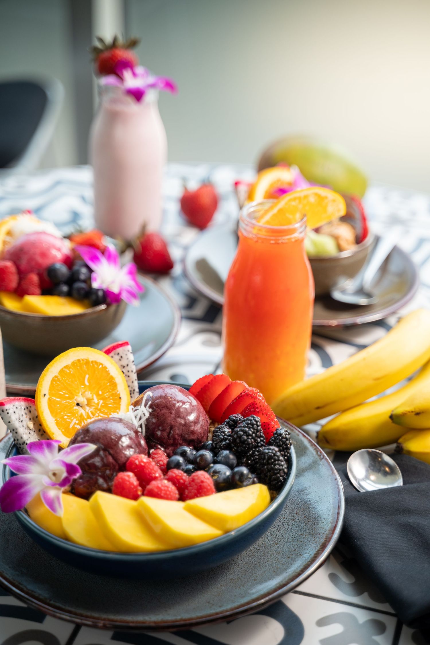 Healthy breakfast spread with fresh fruits, smoothies and acai bowls decorated with orchids.