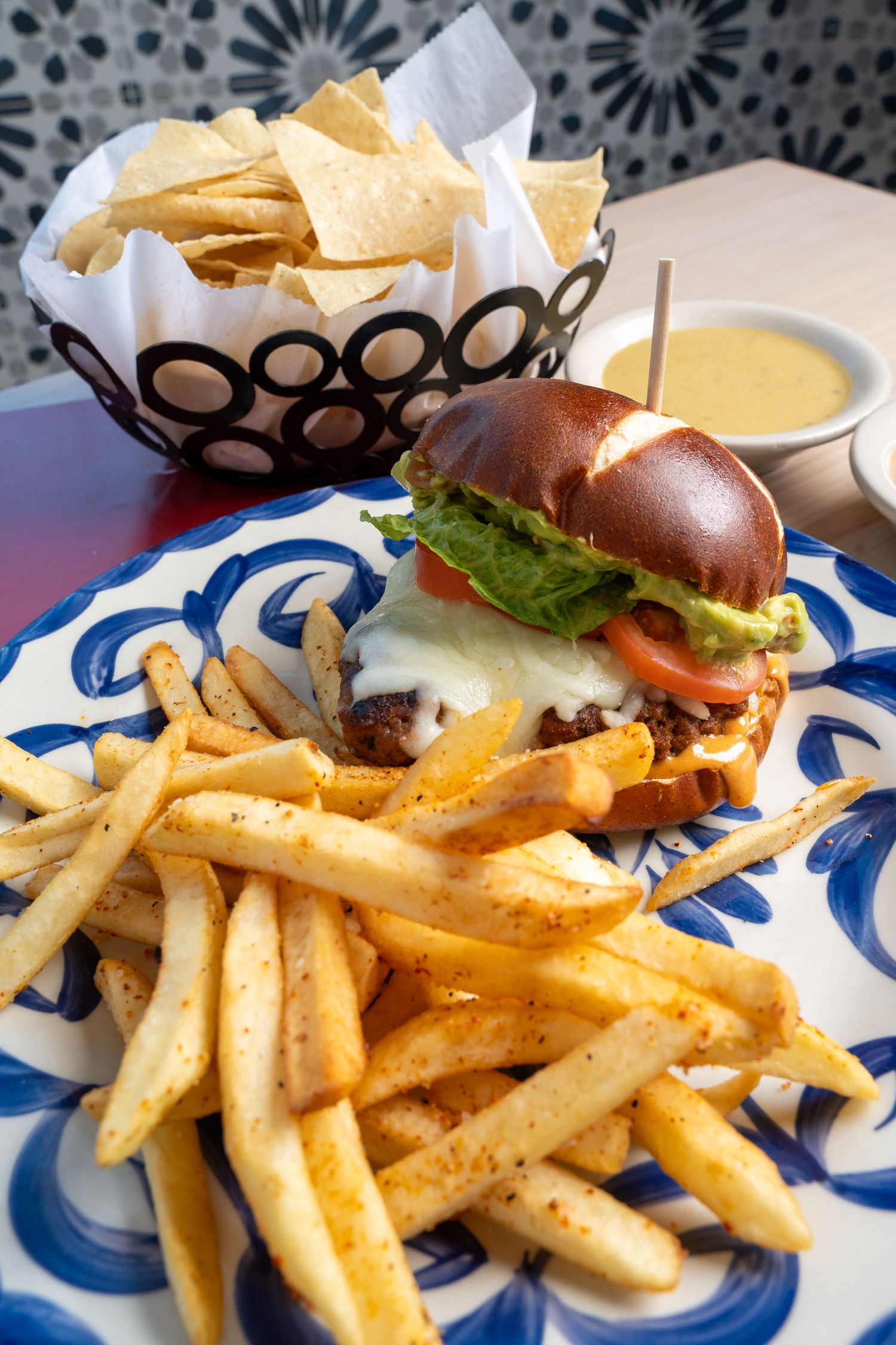 Classic cheeseburger served with crispy golden french fries on a blue and white patterned plate.