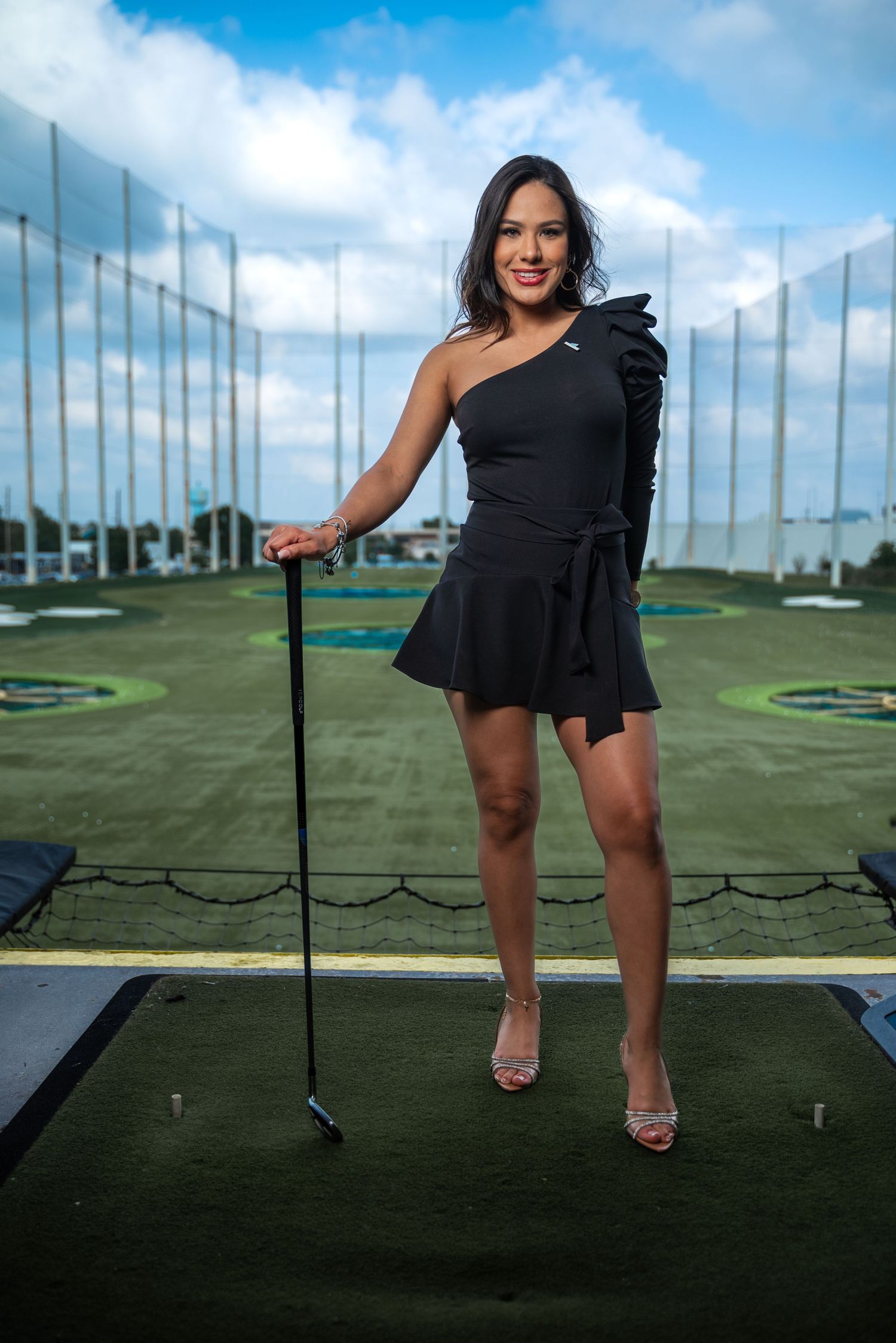 Fashion model posing at Topgolf in Houston, Texas, wearing a stylish and sexy outfit while holding a golf club. Lifestyle branding photo bl