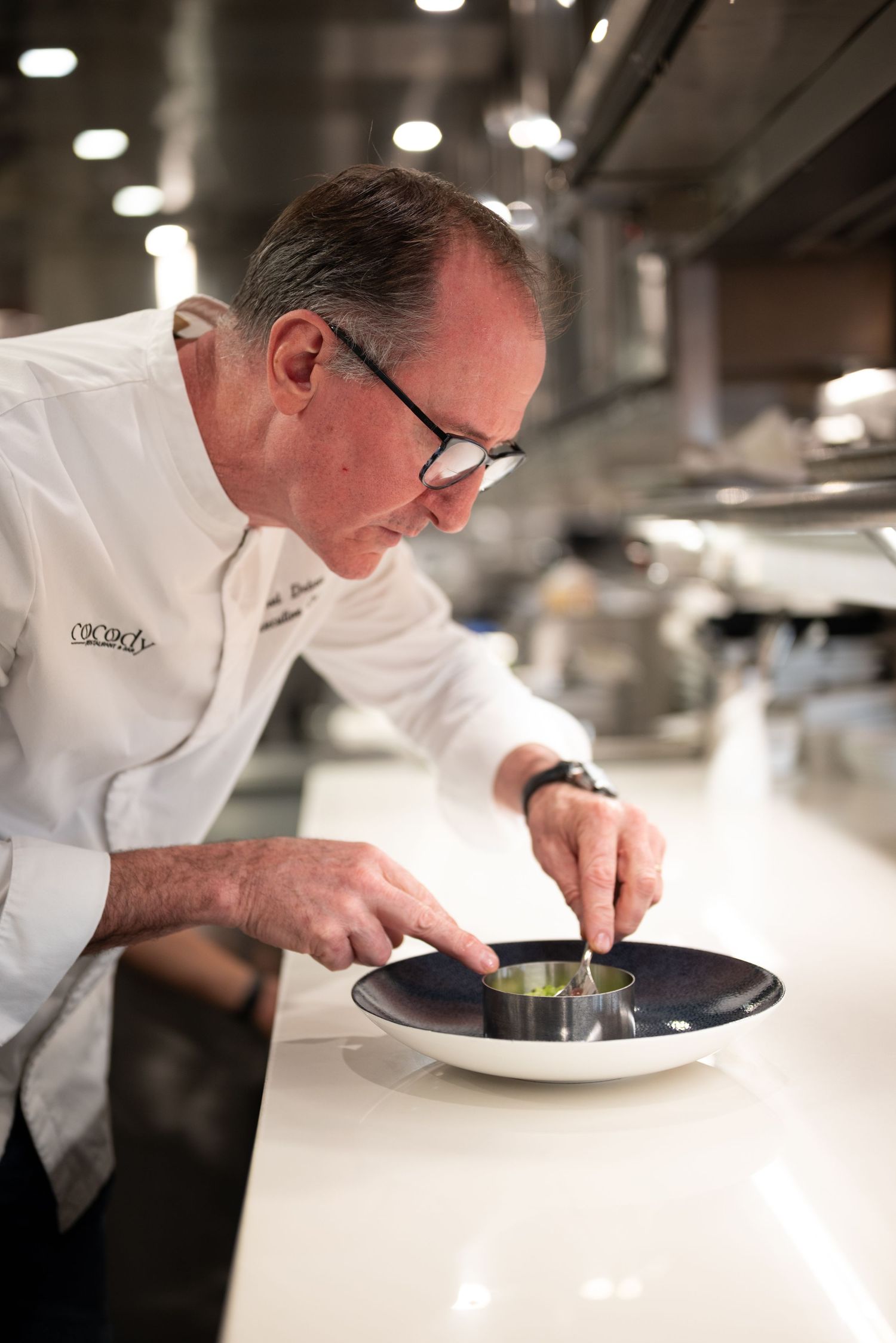 Chef carefully plating a signature dish in a professional restaurant kitchen.