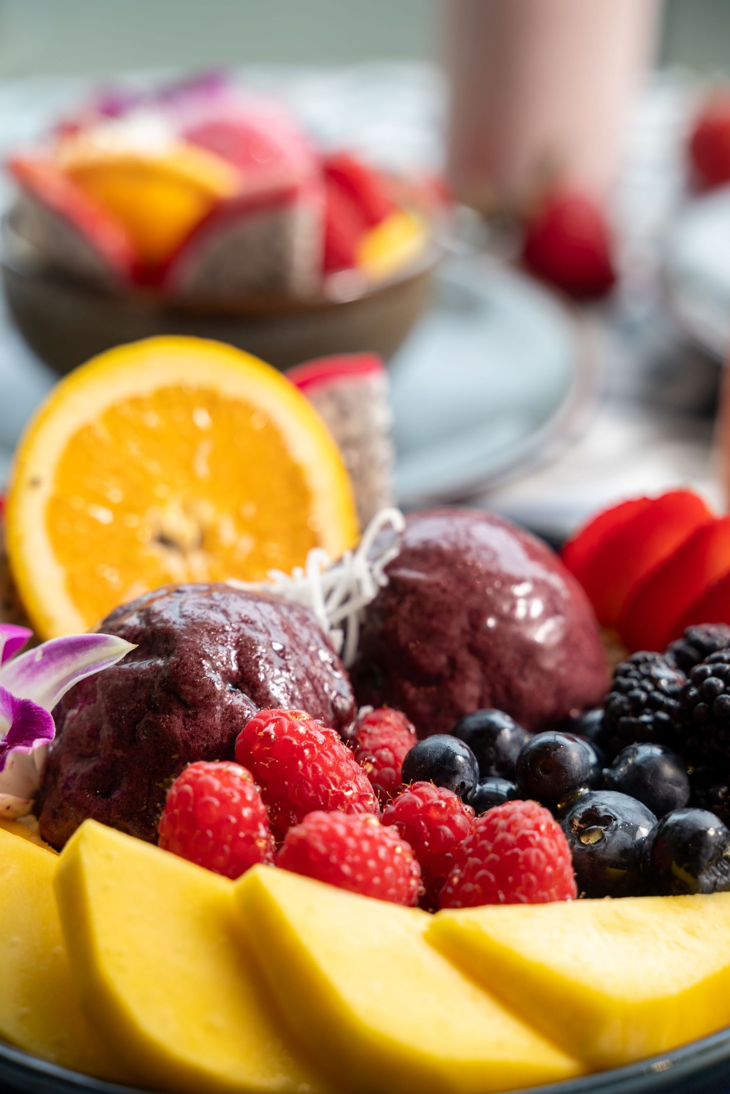 Fresh fruit plate with mango slices, berries, acai scoops and orange segments.