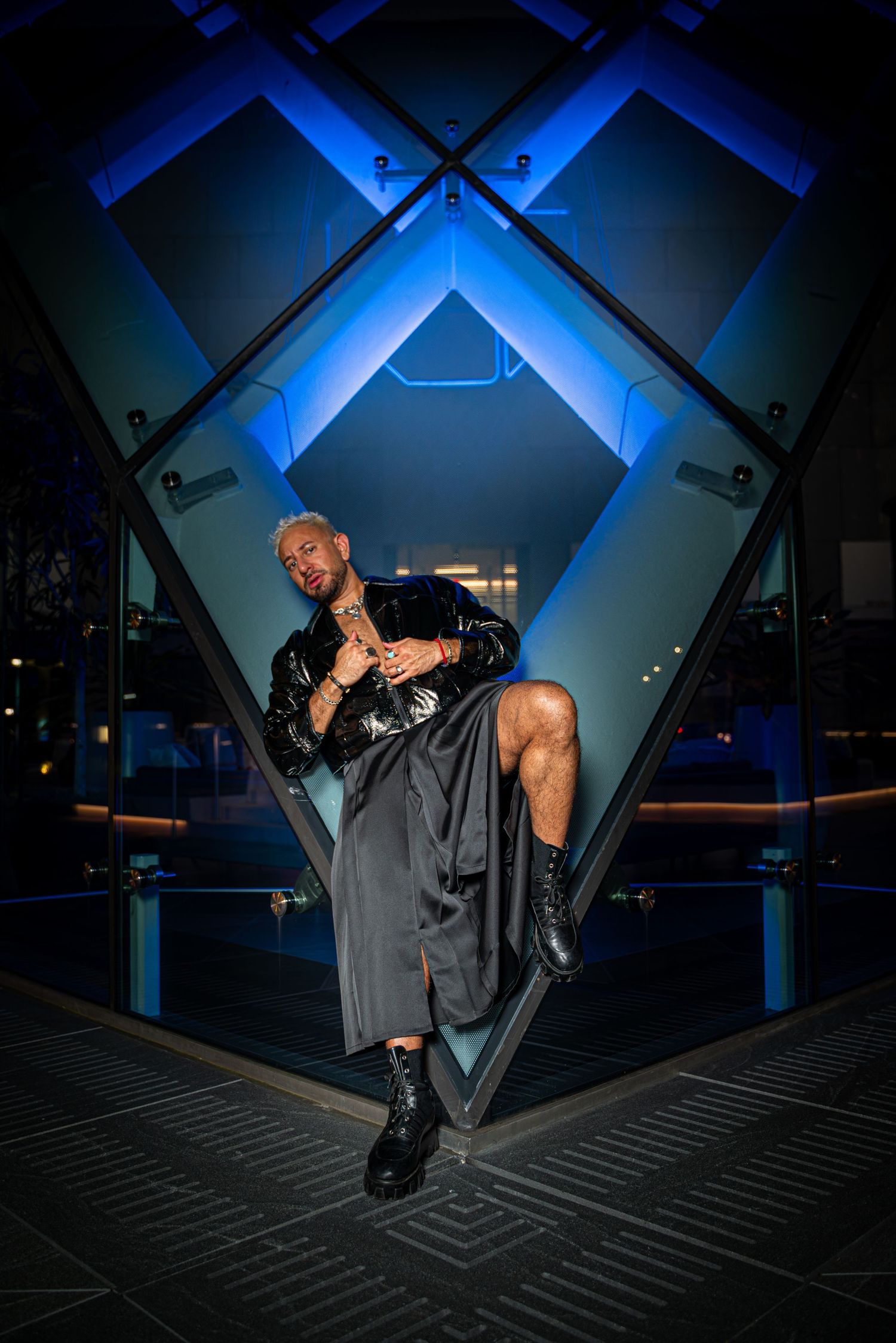 Stylish male model lying on the edge of a rooftop in downtown Houston, Texas, wearing a modern and trendy outfit. Shot with a mix of ambient