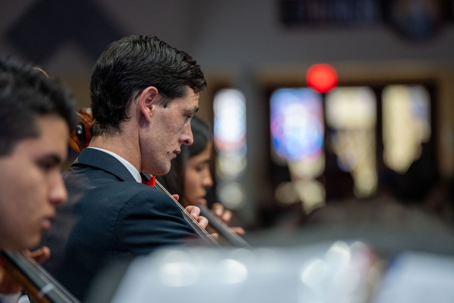 A group of people in business attire sit together at a tech conference or corporate meeting listening to a presentation.