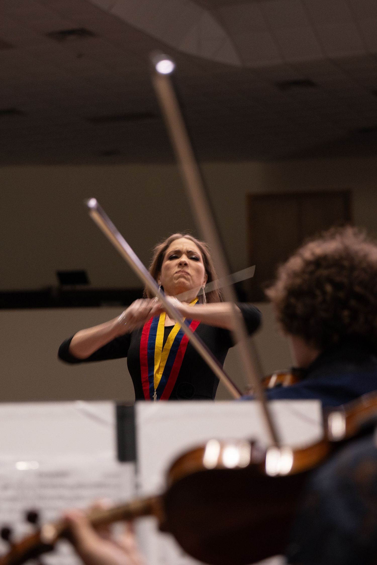 Female orchestra conductor in Houston, Texas, captured mid-performance while leading musicians. Dynamic image showcasing leadership, passion
