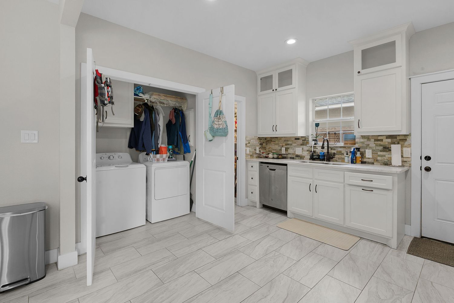Modern kitchen with white cabinets, stainless steel appliances, and light wood flooring.