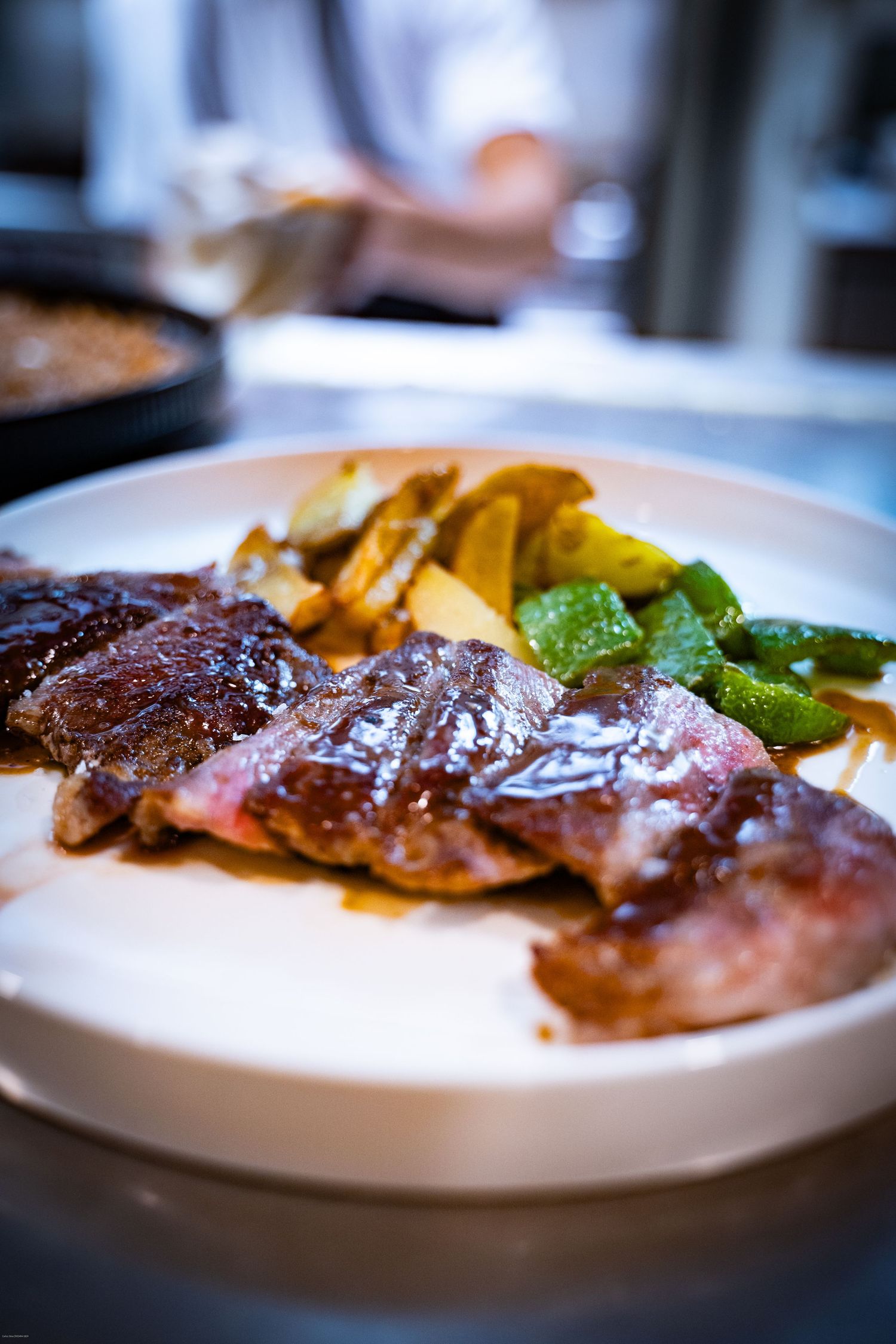 Juicy grilled steak served on white plates with colorful vegetables and garnishes in elegant presentation.