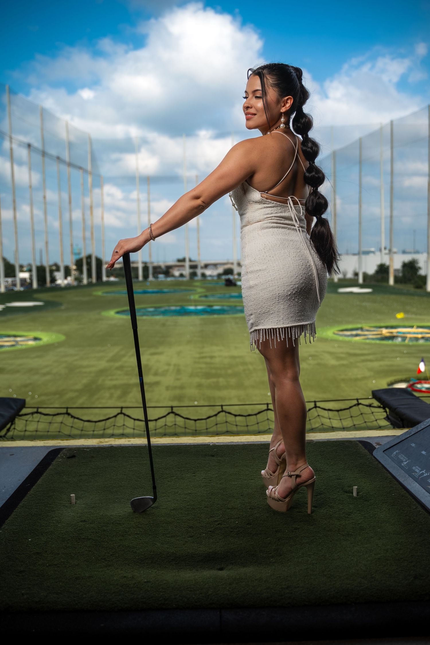 Fashion model posing at Topgolf in Houston, Texas, wearing a stylish and sexy outfit while holding a golf club. Lifestyle branding photo bl