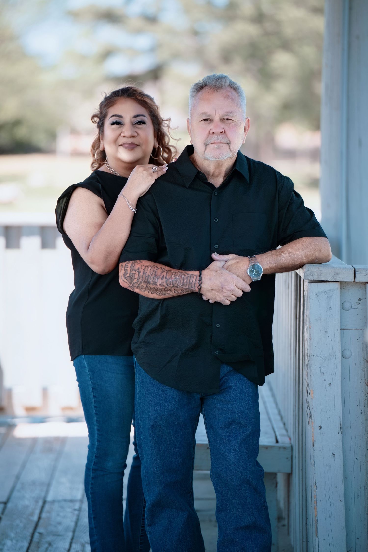 Two people sharing warm embrace on wooden deck outdoors.