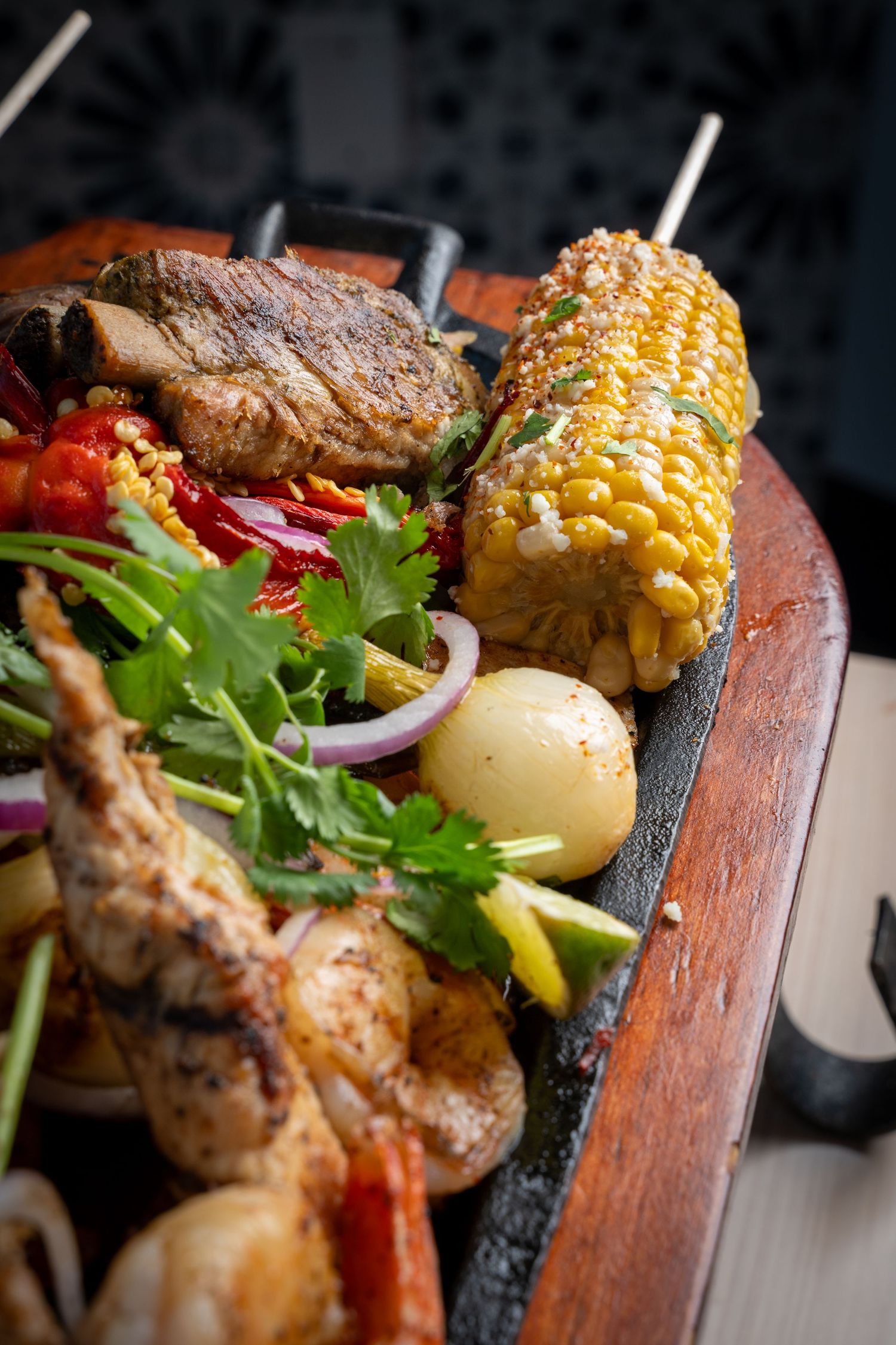 Close-up of grilled kebab skewers featuring meat, shrimp, and vegetables with fresh herbs.
