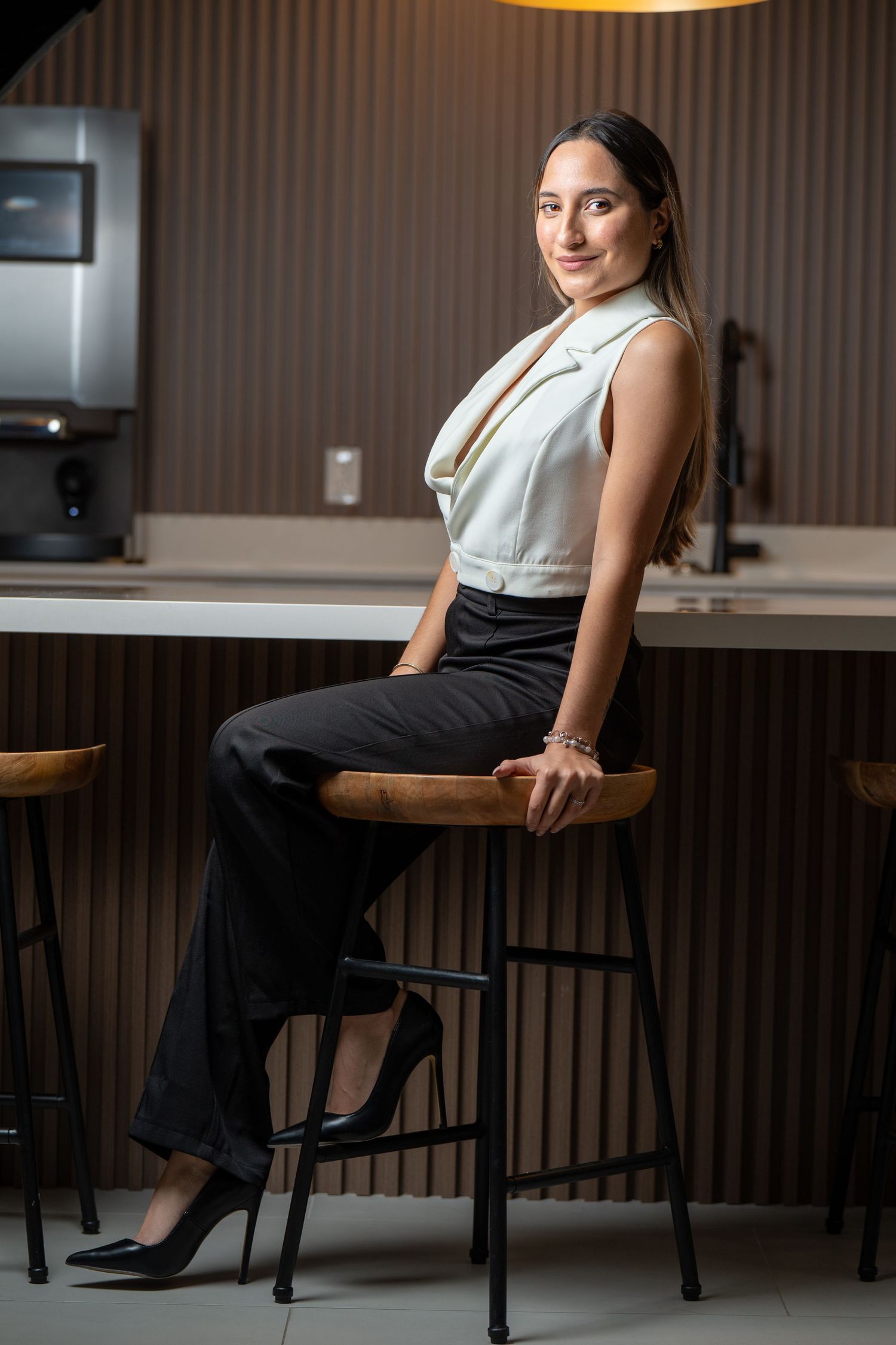 Lifestyle portrait of a health and life insurance professional in Houston, Texas, posing on a bench in an office setting with earthy tones
