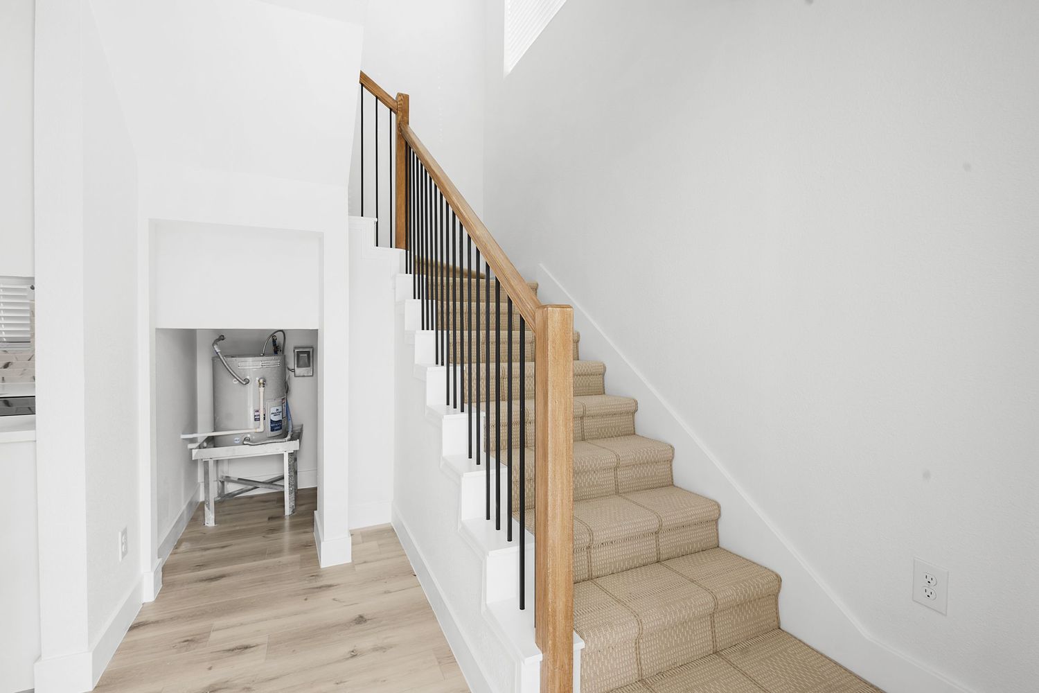 Bright white staircase with wooden steps and metal railings leading upstairs in a contemporary home.