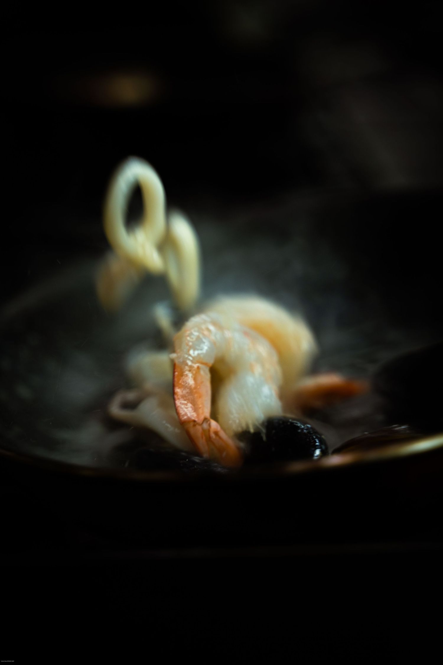 Artistic close-up of sushi pieces on a dark plate with dramatic lighting.