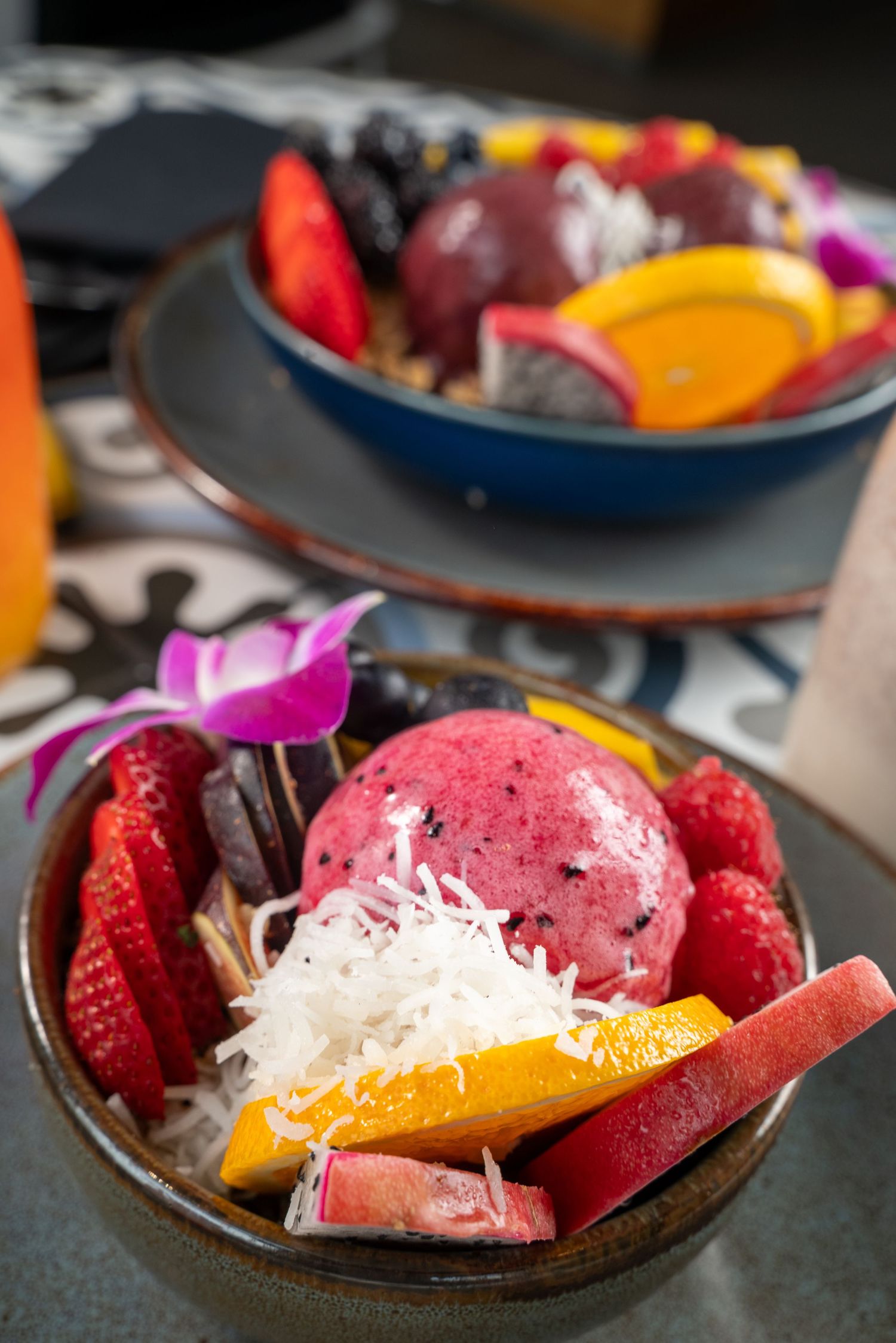 Acai bowl with fresh berries, orange slices and shredded coconut in ceramic bowl.