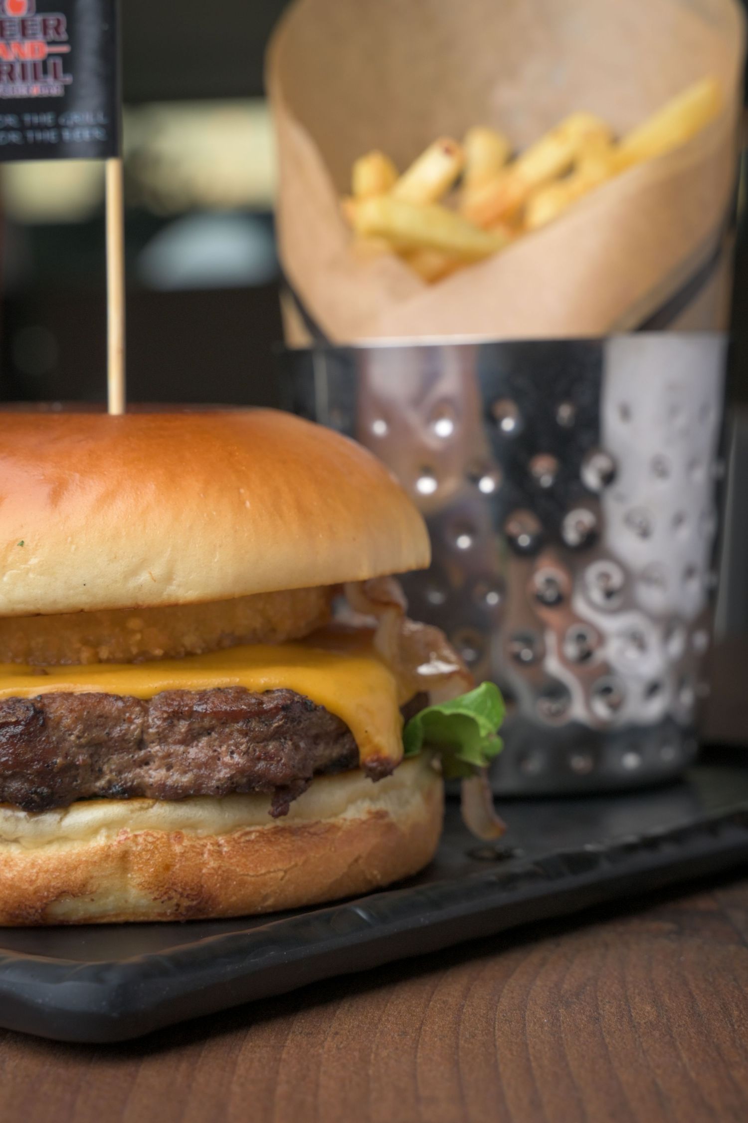Cheeseburger with melted American cheese on toasted bun served on black slate.