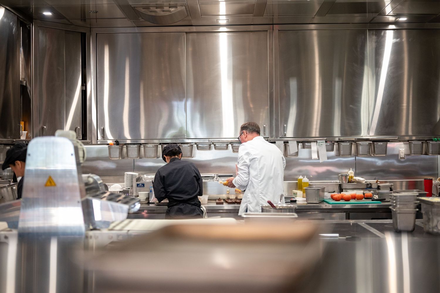 Two chefs working in a modern stainless steel commercial kitchen preparing dishes in a professional restaurant.