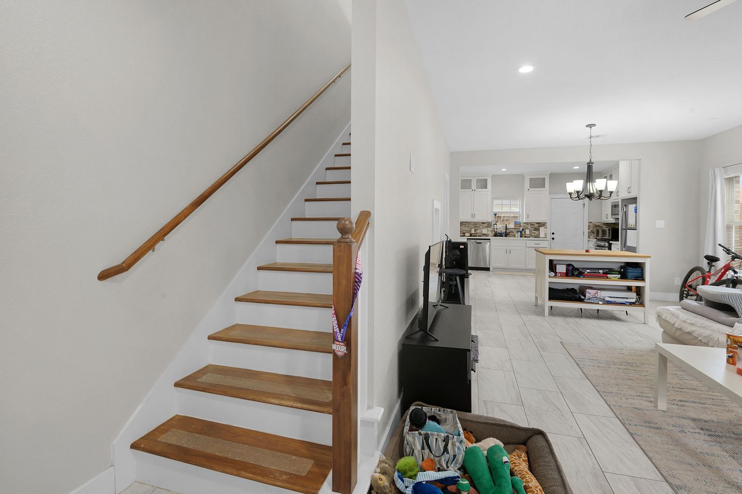 Wooden staircase with white walls leading to open concept living area.