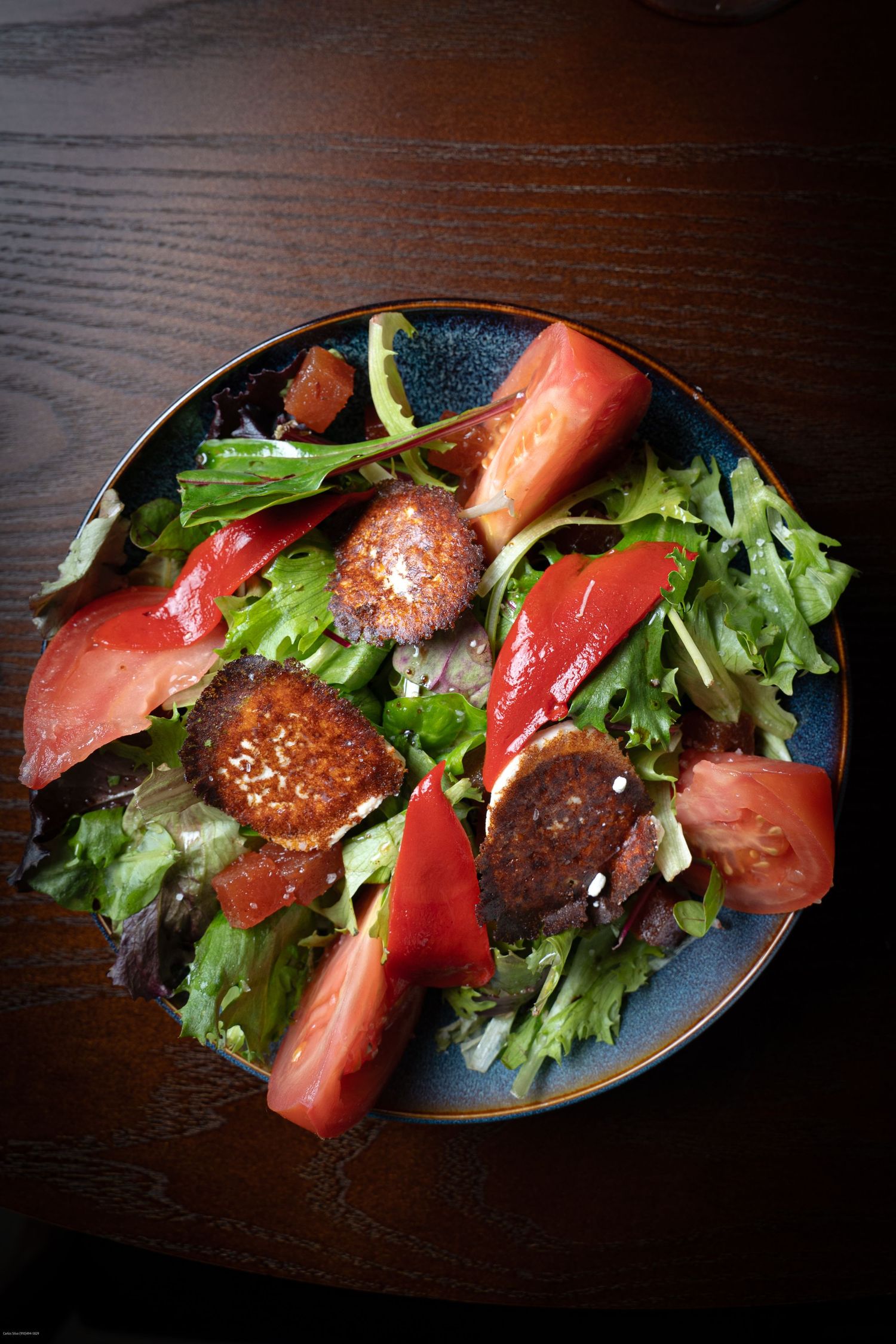 Fresh salad with seared tuna, watermelon, and mixed greens served on a dark oval plate.
